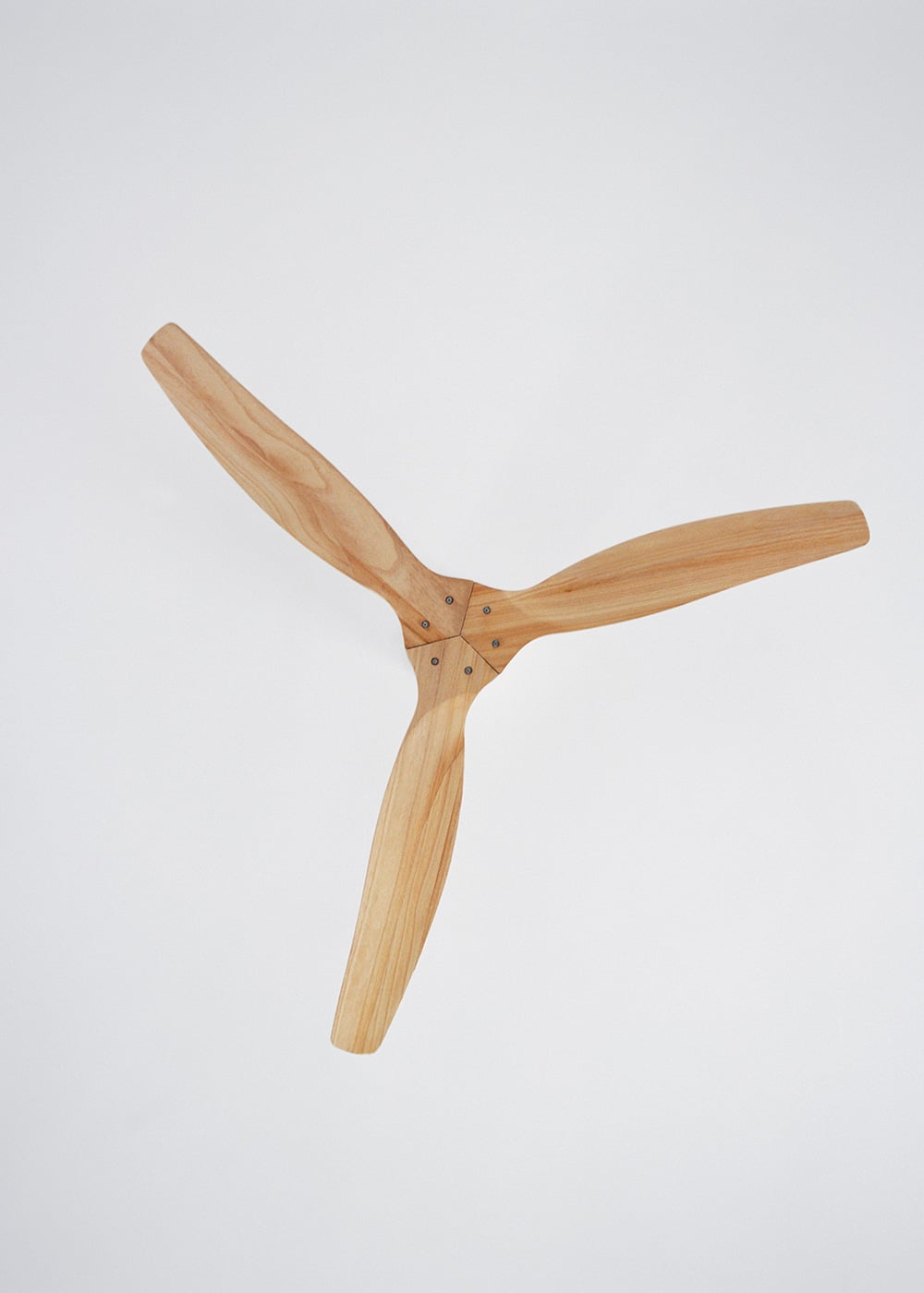Una pala de ventilador de madera de tres aspas sobre fondo blanco.