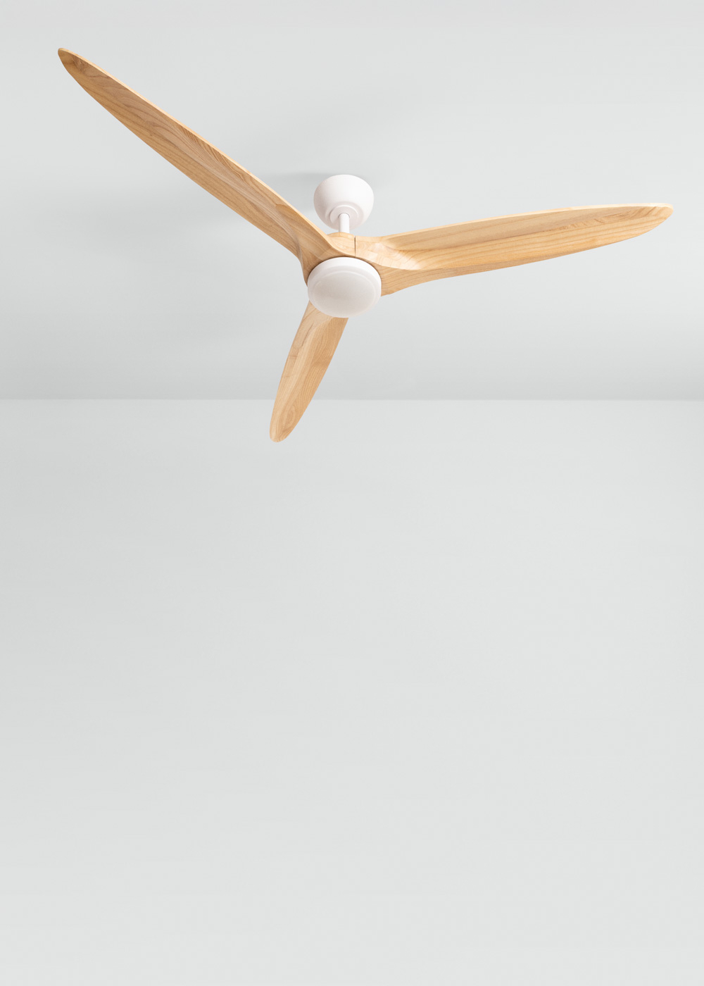 Un ventilador de techo moderno con tres aspas de madera y carcasa blanca.