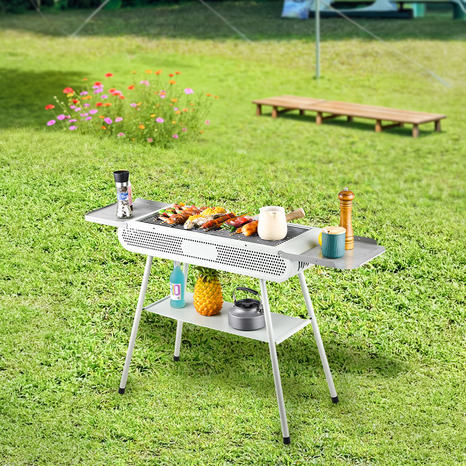 Una parrilla blanca con comida encima se asienta sobre hierba verde. Flores y un banco al fondo.