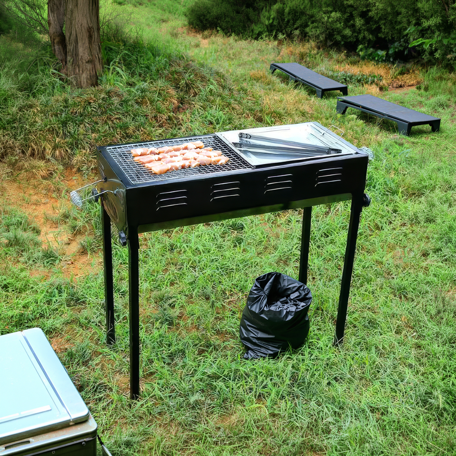 Ein Grill mit rohem Hühnchen steht im Gras. daneben ein Müllsack.