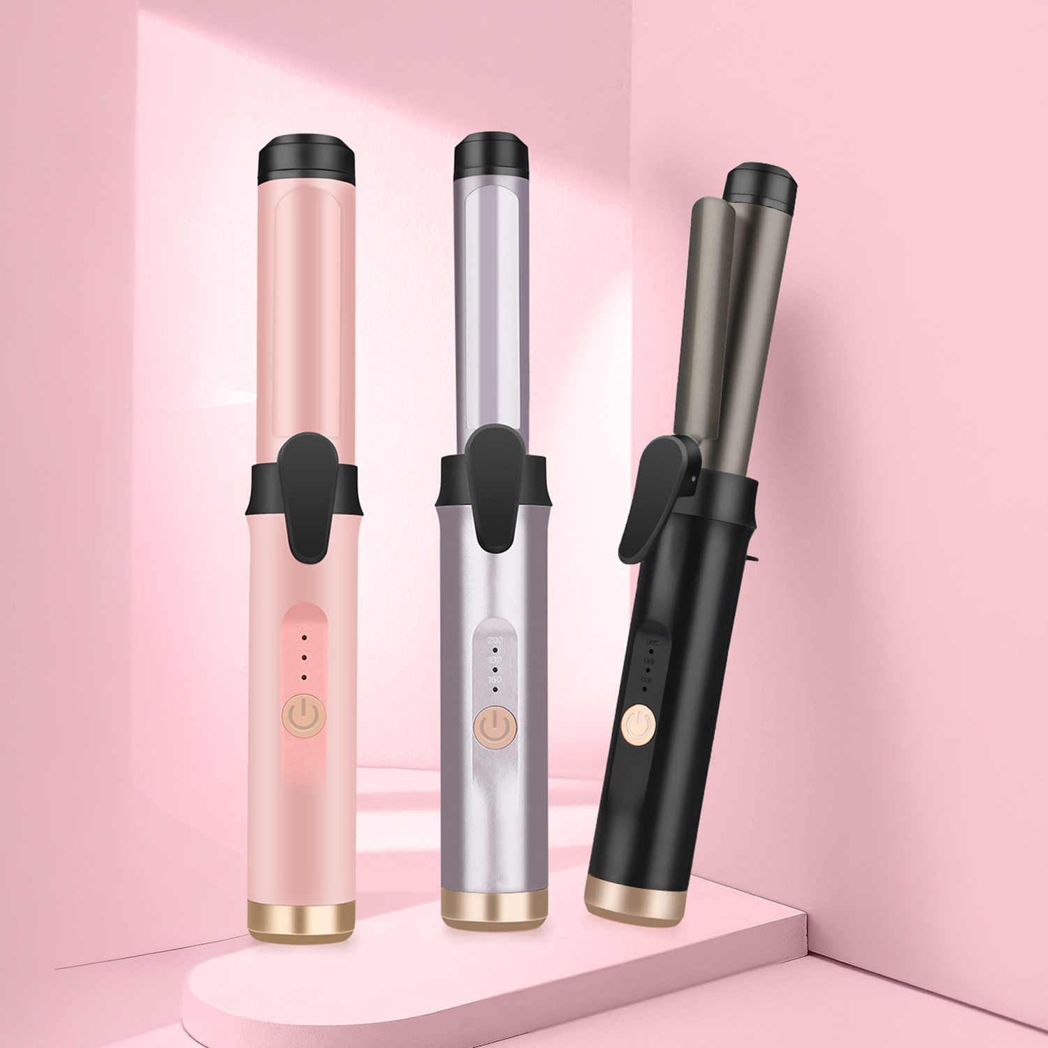 Tres rizadores de pelo en rosa, plateado y negro sobre pedestales rosas.