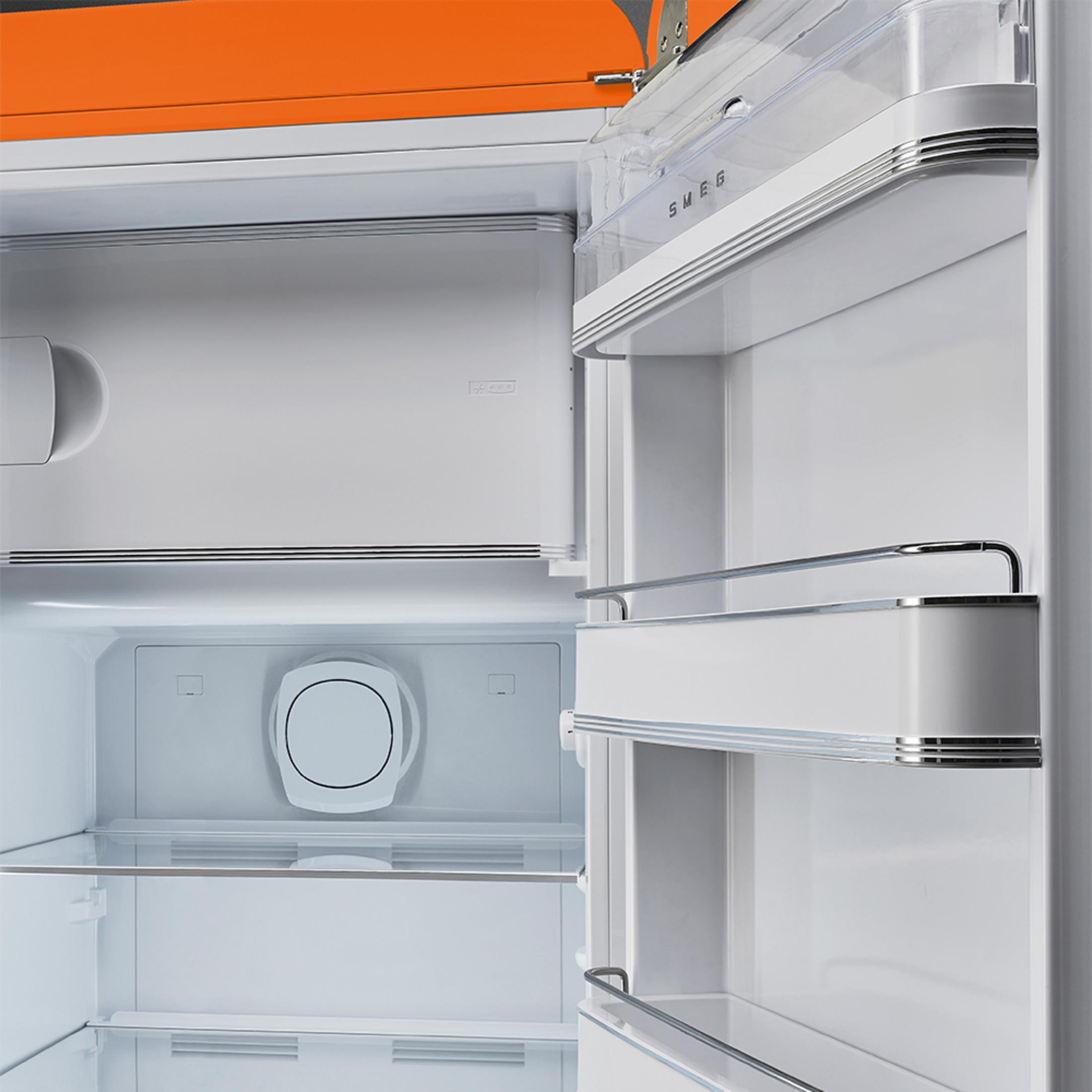 Vista interior de un refrigerador blanco abierto con tapa naranja. Se ven estantes y compartimentos.