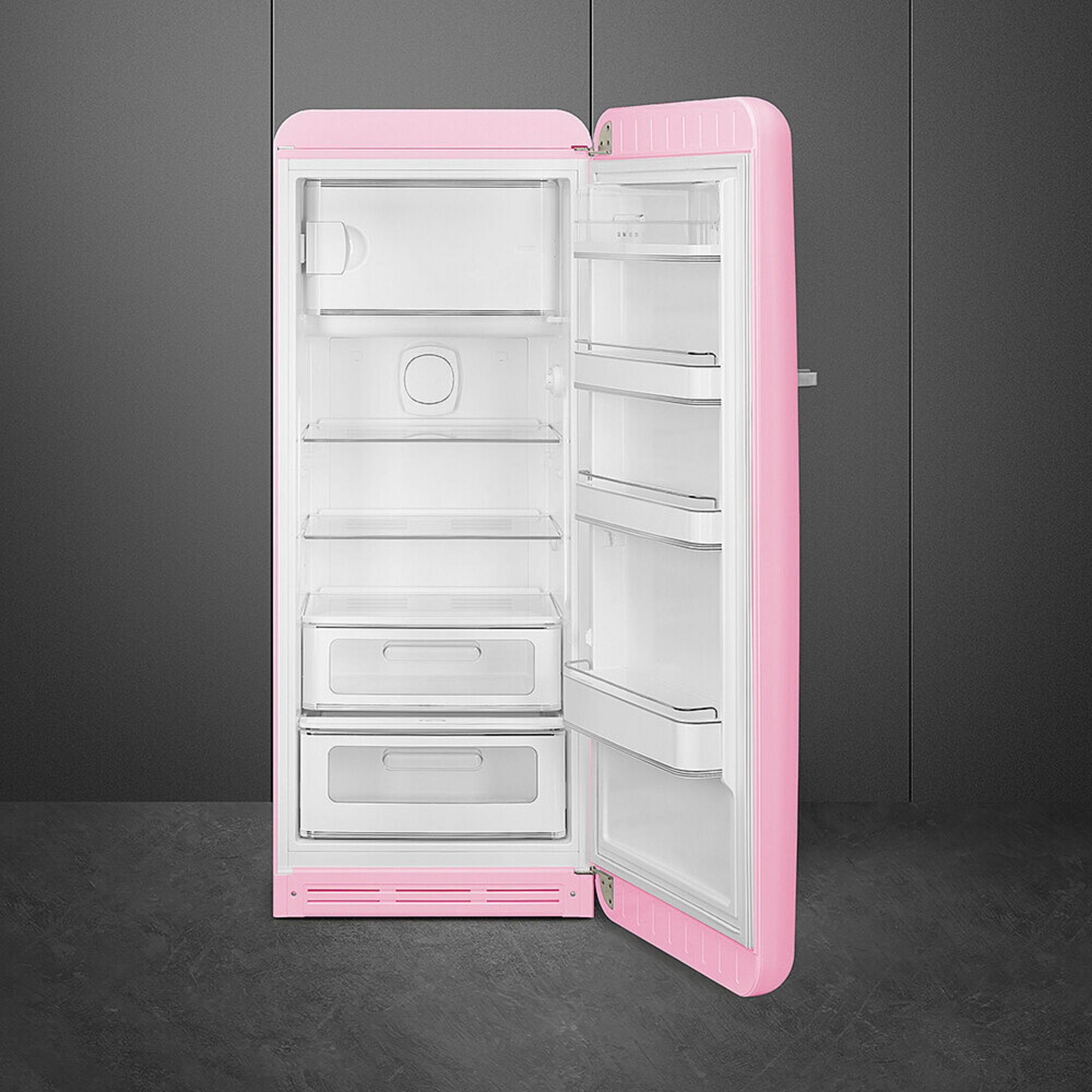 Un refrigerador rosa abierto con estantes y cajones blancos.