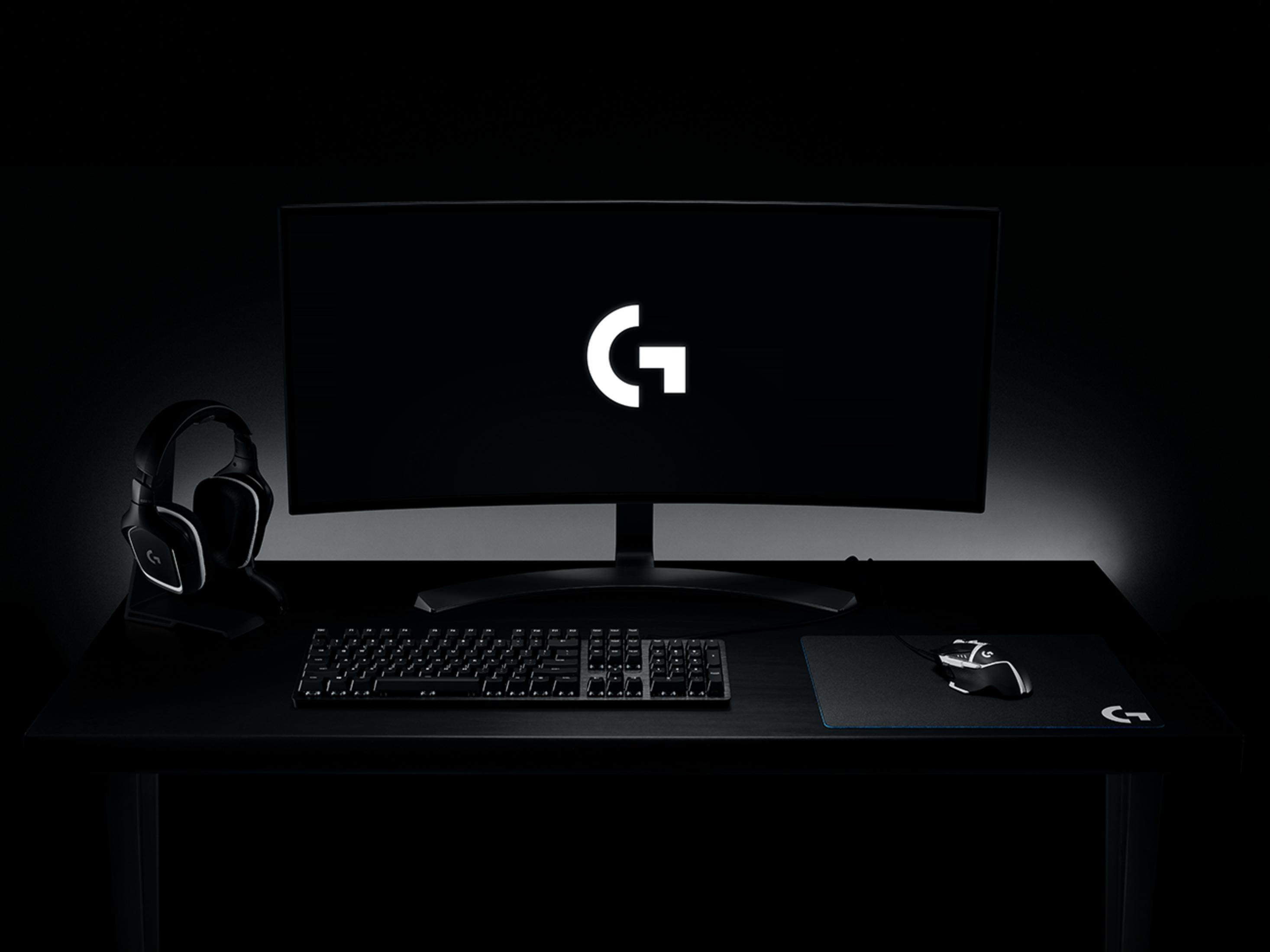Una scrivania nera con monitor, tastiera, mouse, cuffie e tappetino.