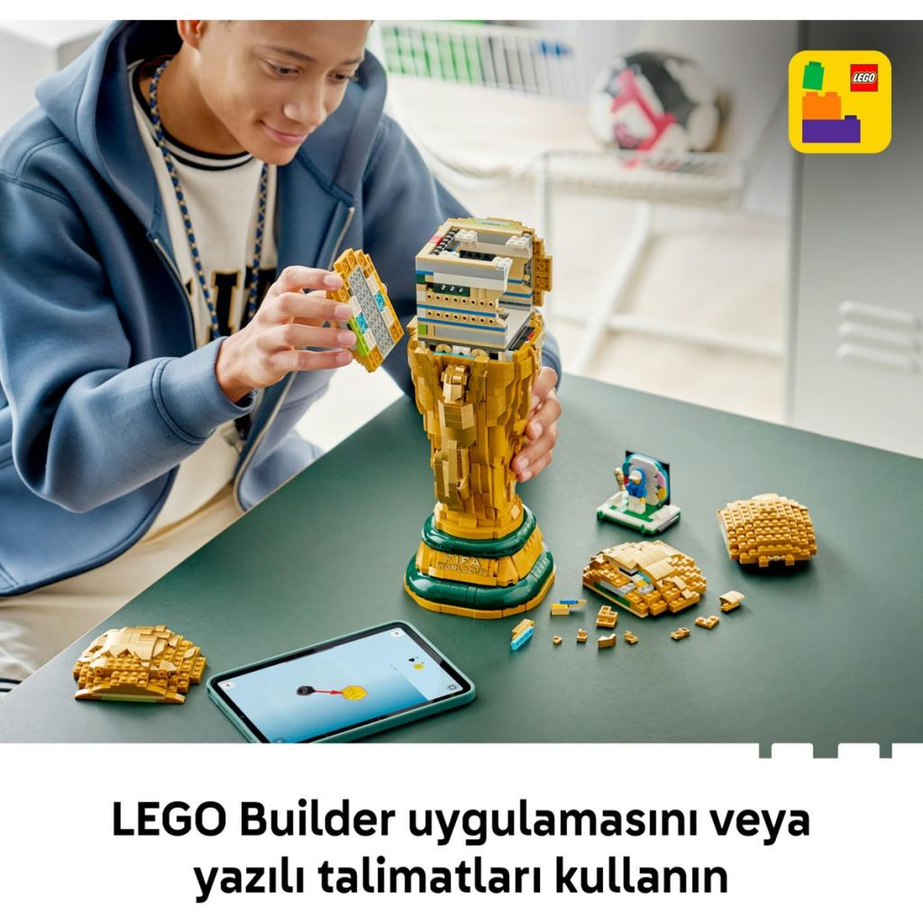 Chłopiec buduje trofeum LEGO z tabletem w pobliżu.