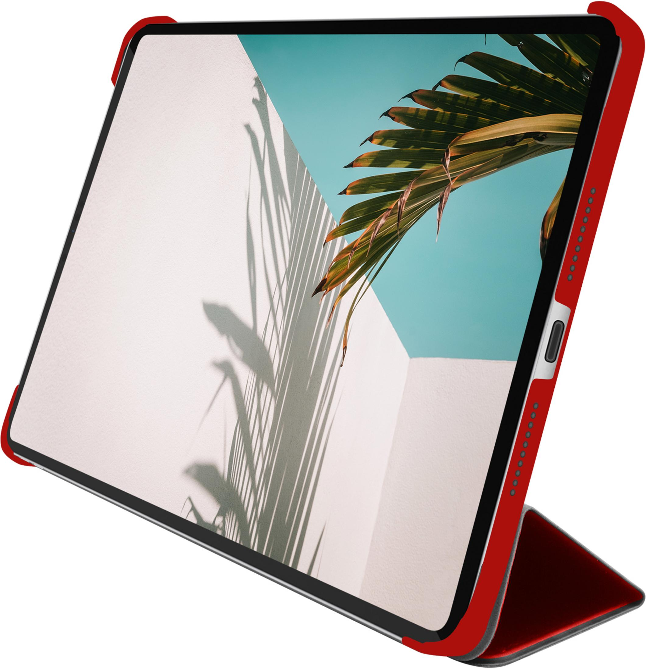 Ein rotes Tablet im Ständer mit einem Palmenblatt und Schatten auf einer weißen Wand.