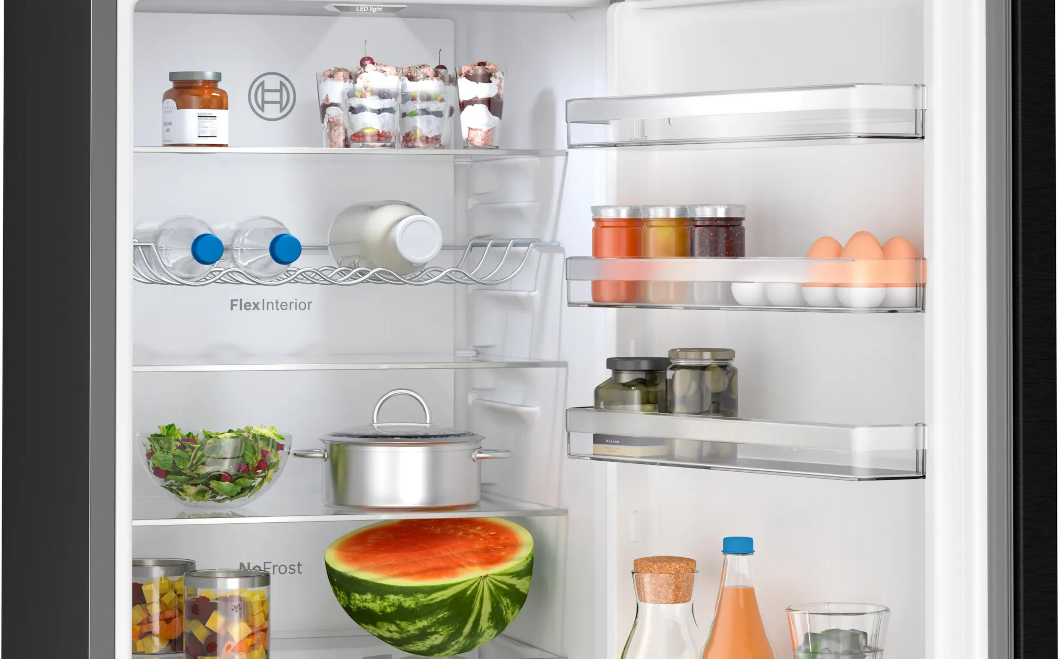 Ein offener Kühlschrank mit Gläsern, Flaschen, Eiern, Obst, Gemüse und Töpfen.