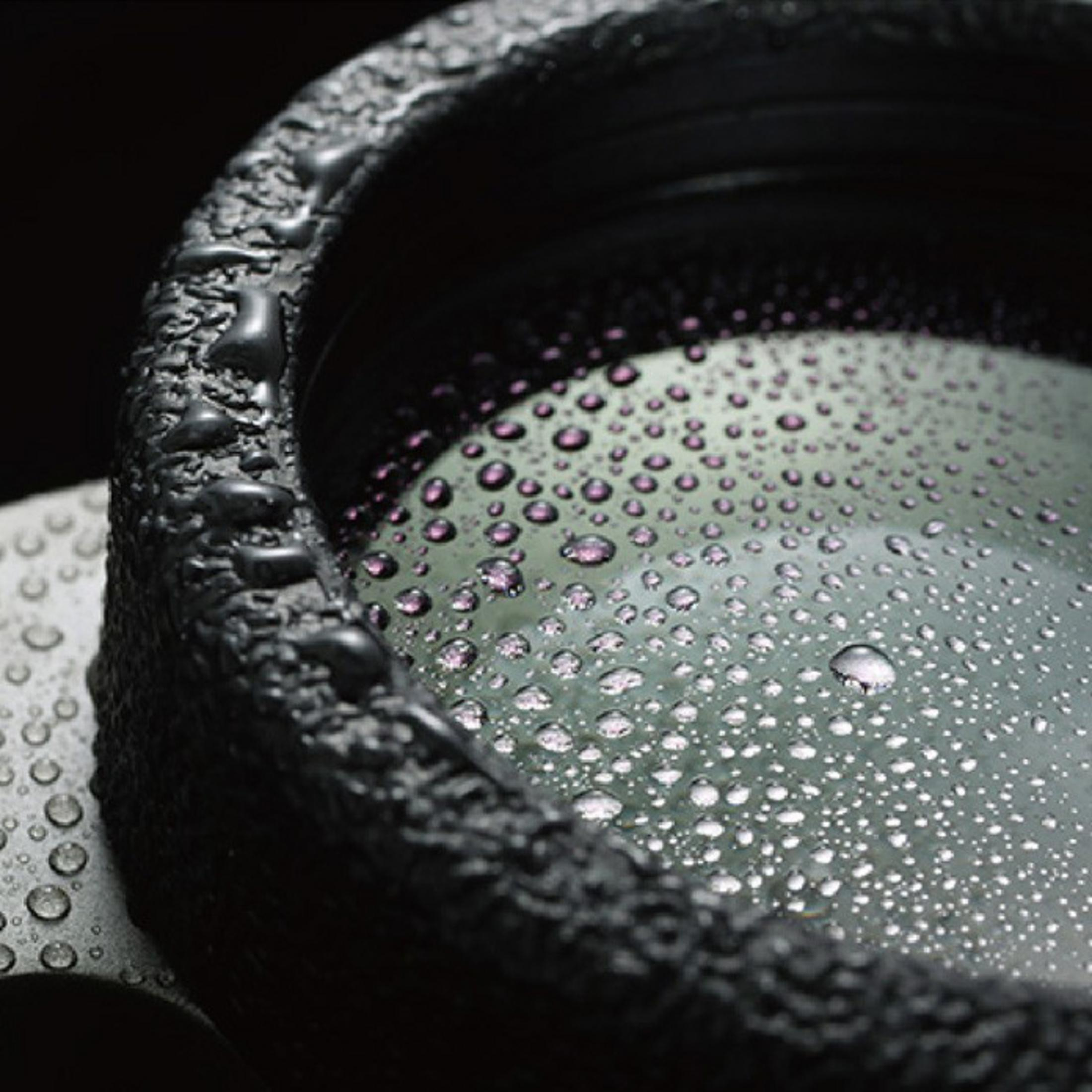Gocce d'acqua su superficie scura texturizzata e lente.