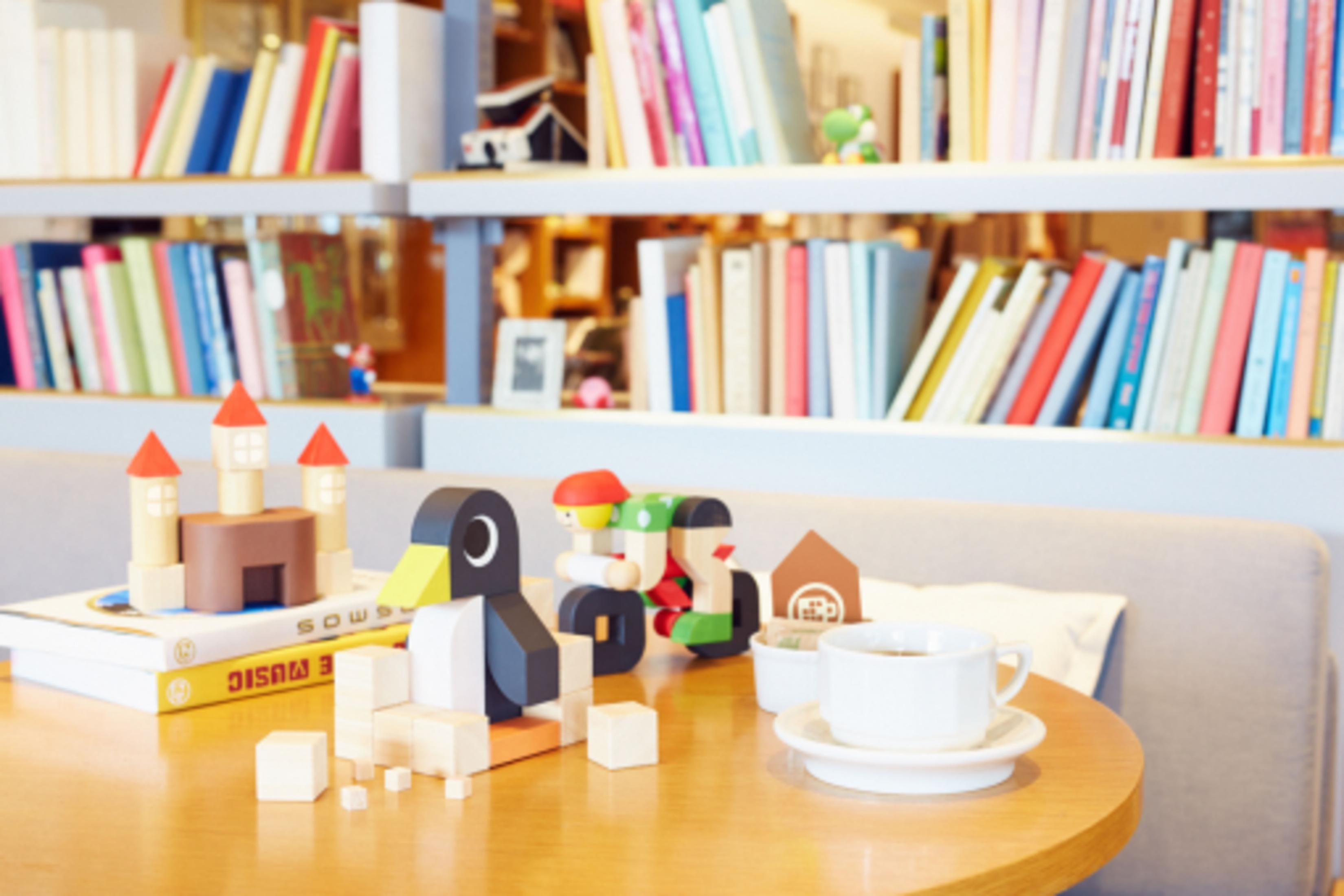 Juguetes de madera: pingüino, castillo, figuras sobre libros con té.