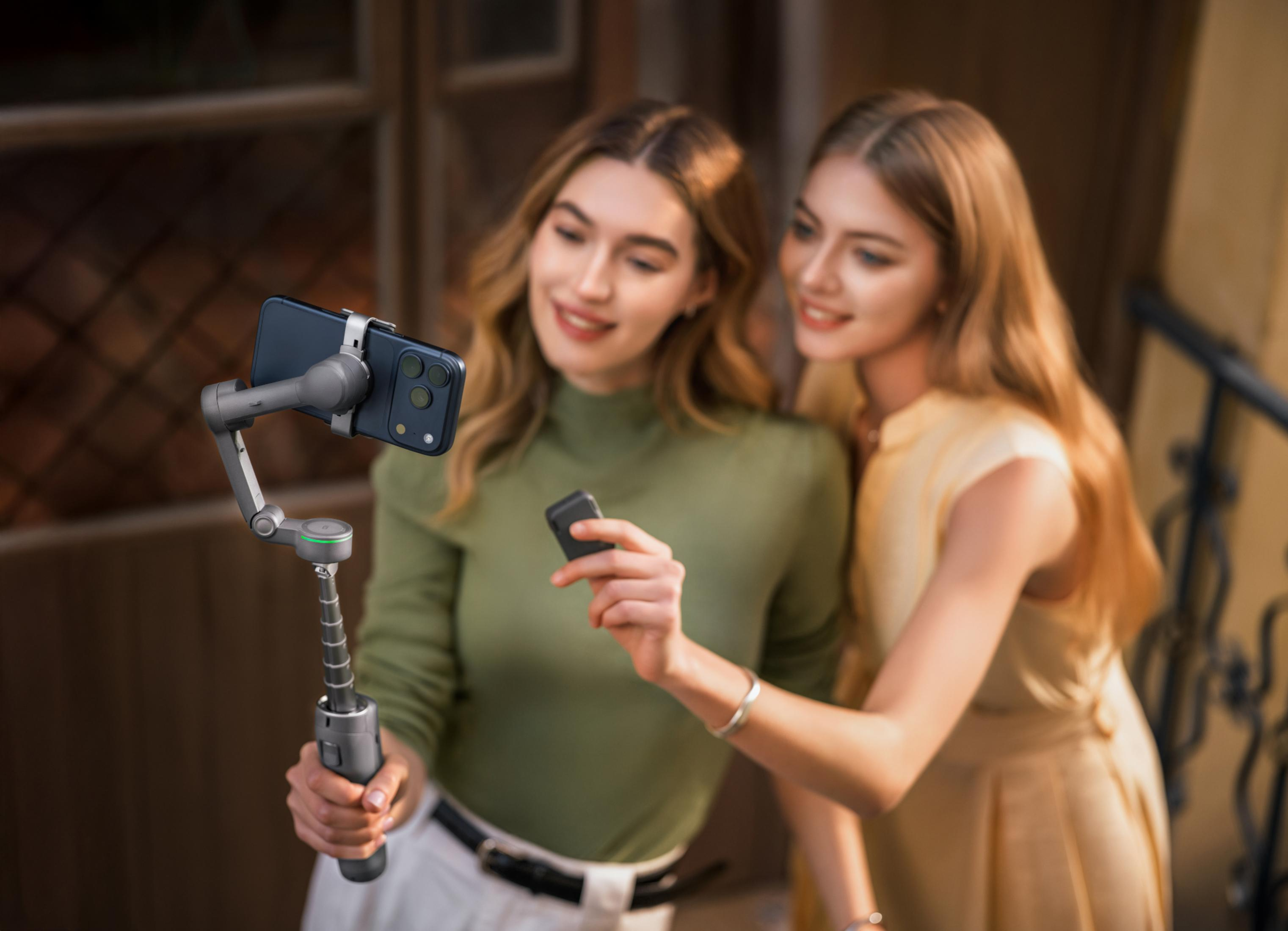 İki kadın gimbal ve telefon kullanarak selfie çekiyor.