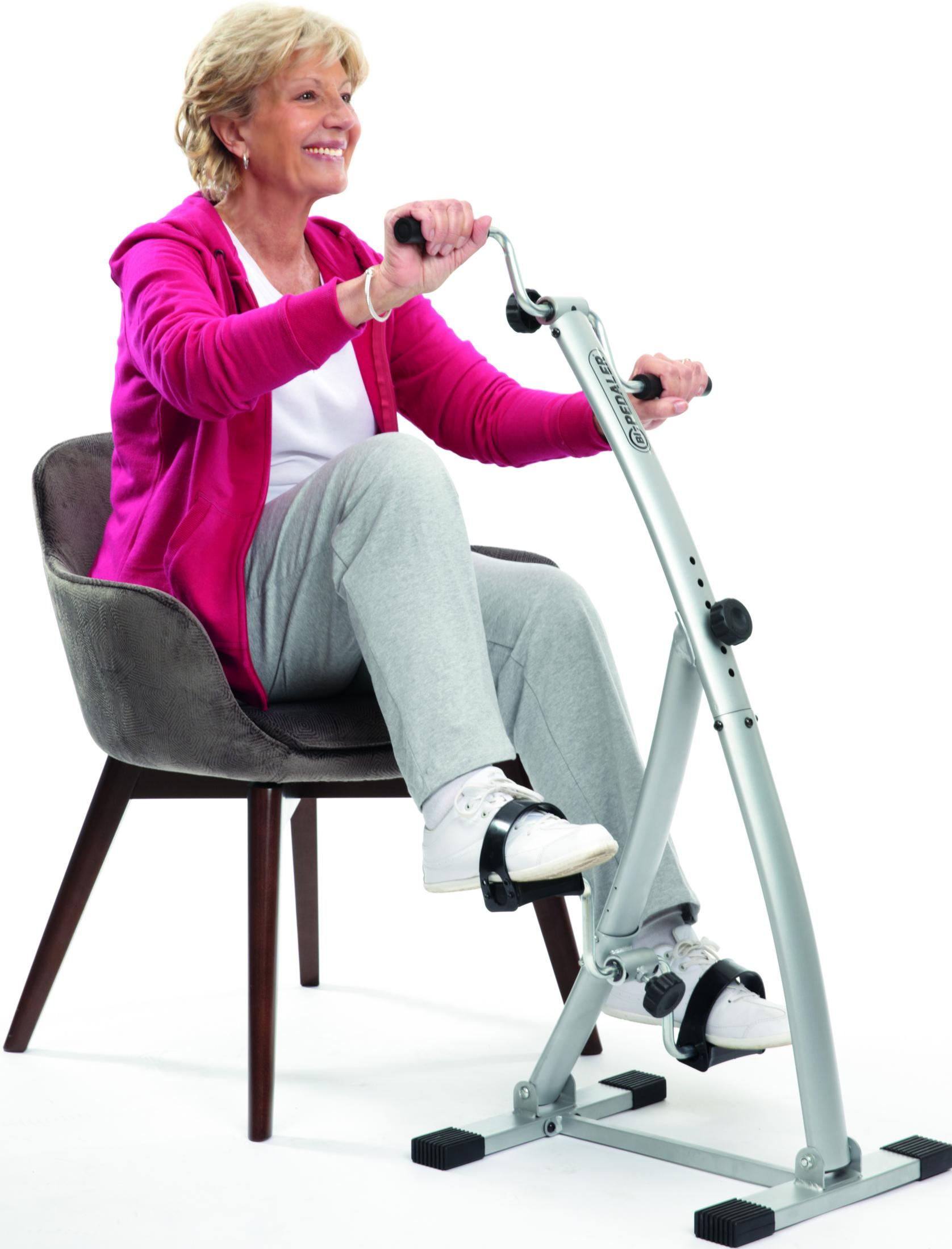 Eine Frau auf einem Stuhl trainiert auf einem silbernen Pedal-Trainer.