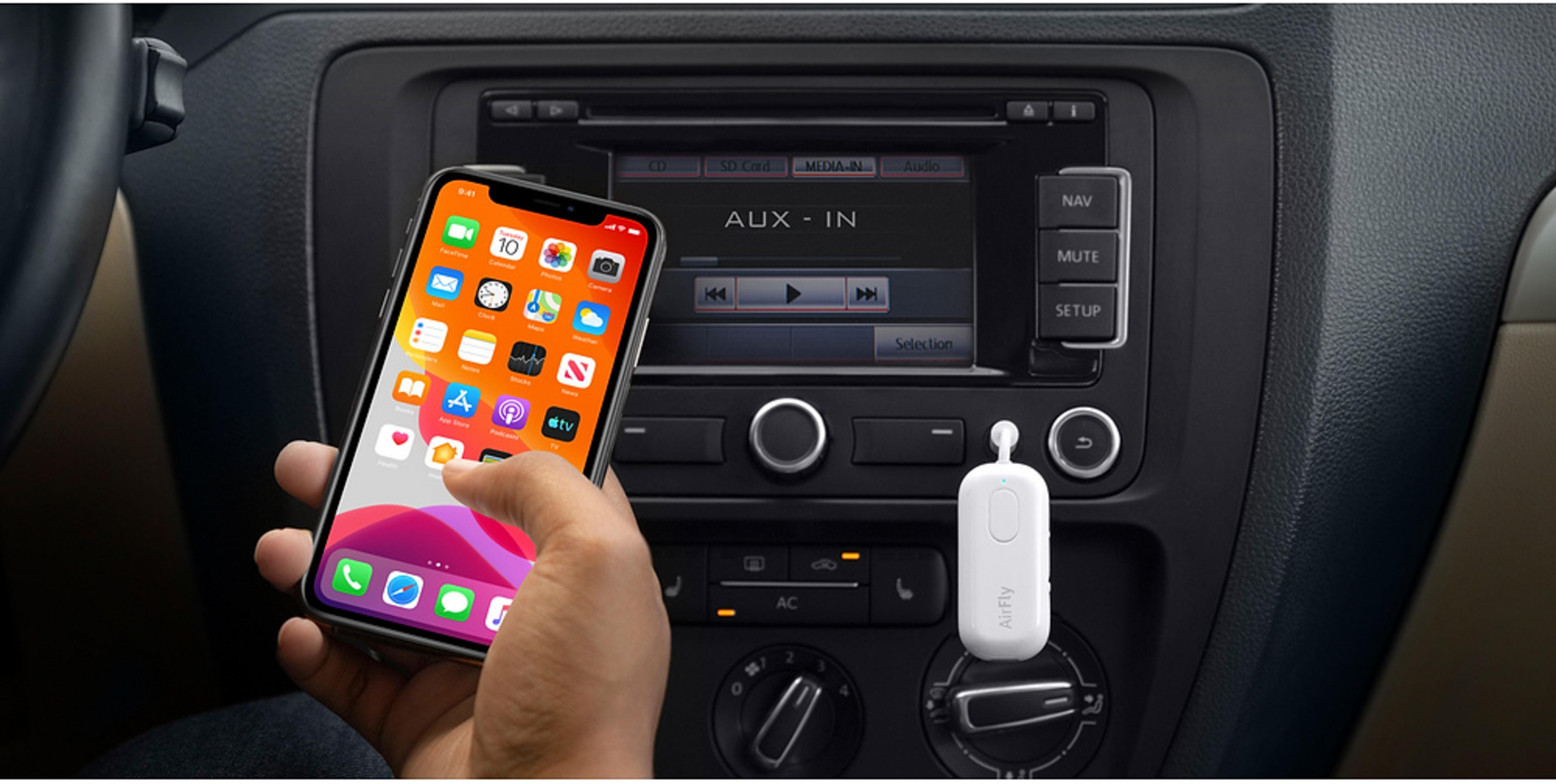 Eine Hand hält ein iPhone vor das Autoradio mit AUX-IN-Anzeige.