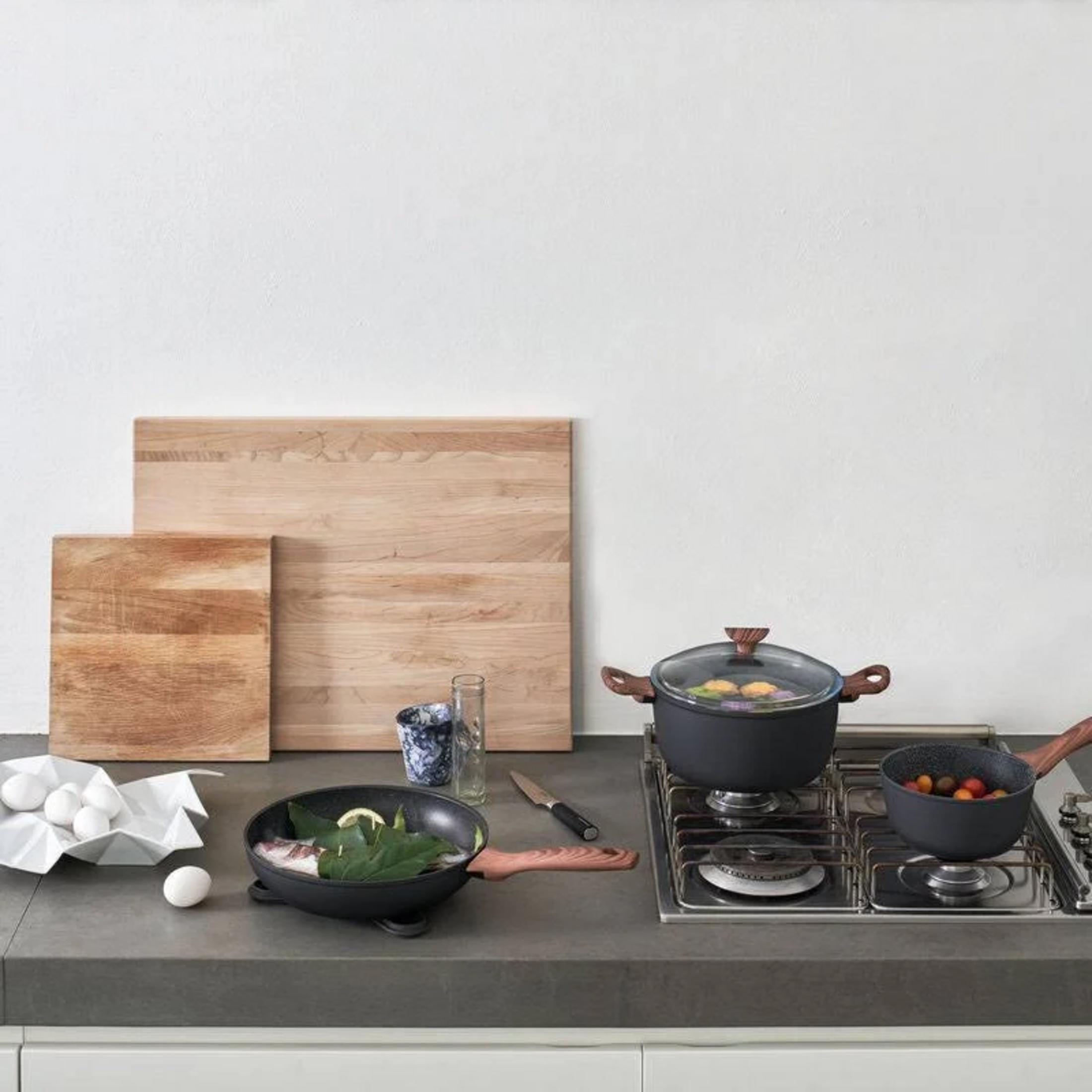 Comptoir de cuisine avec ustensiles de cuisine : planches à découper, œufs, poêle et casseroles sur la cuisinière.