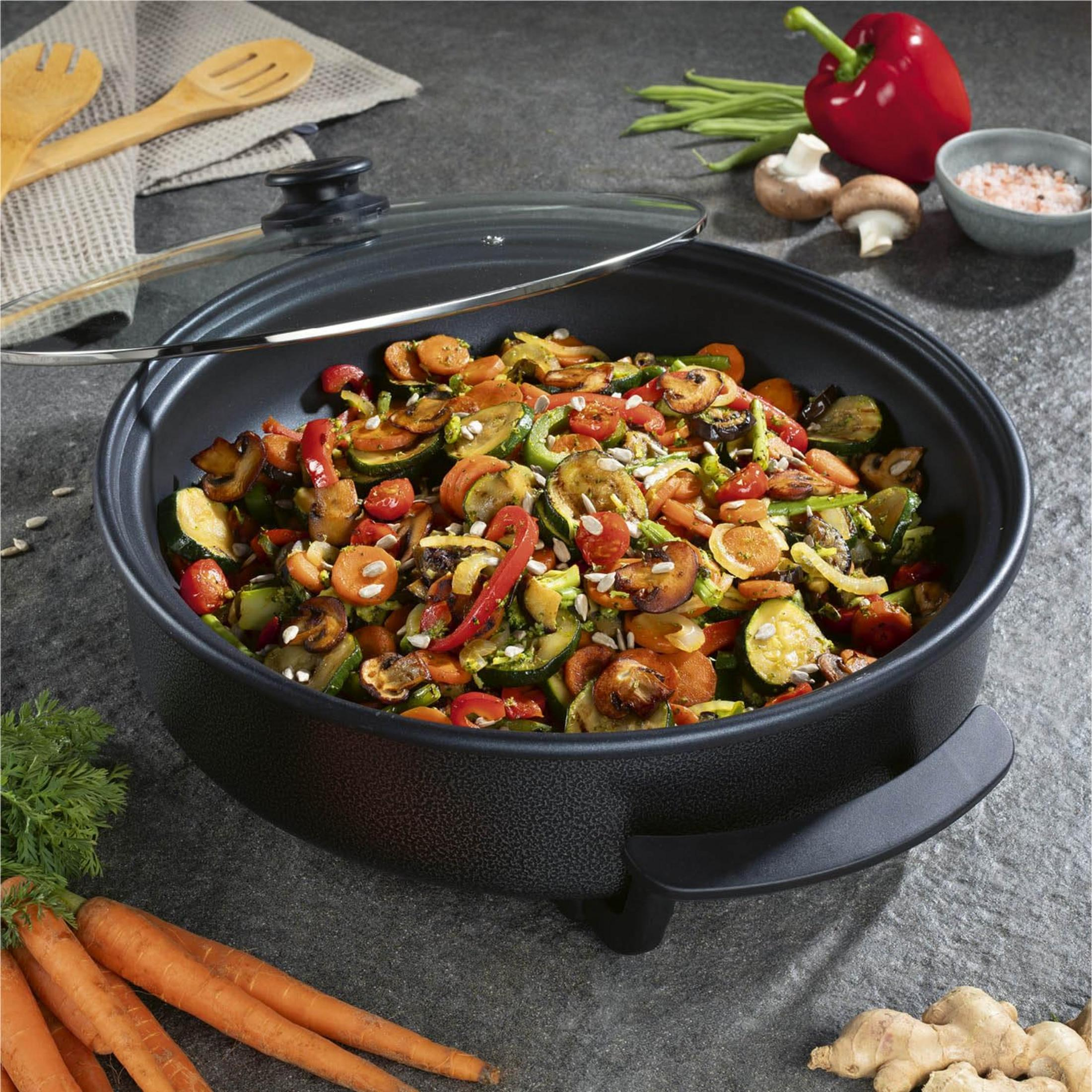 Bunte Gemüsepfanne mit Karotten, Zucchini, Paprika und Pilzen in einer Pfanne.