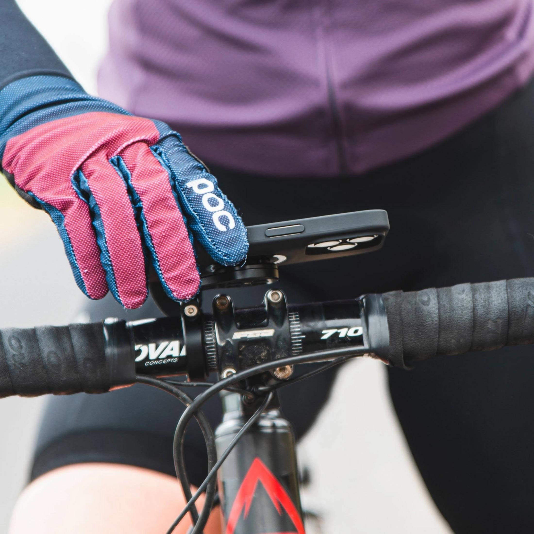 Radfahrerhand mit Handschuh hält Smartphone-Halterung am Fahrradlenker.