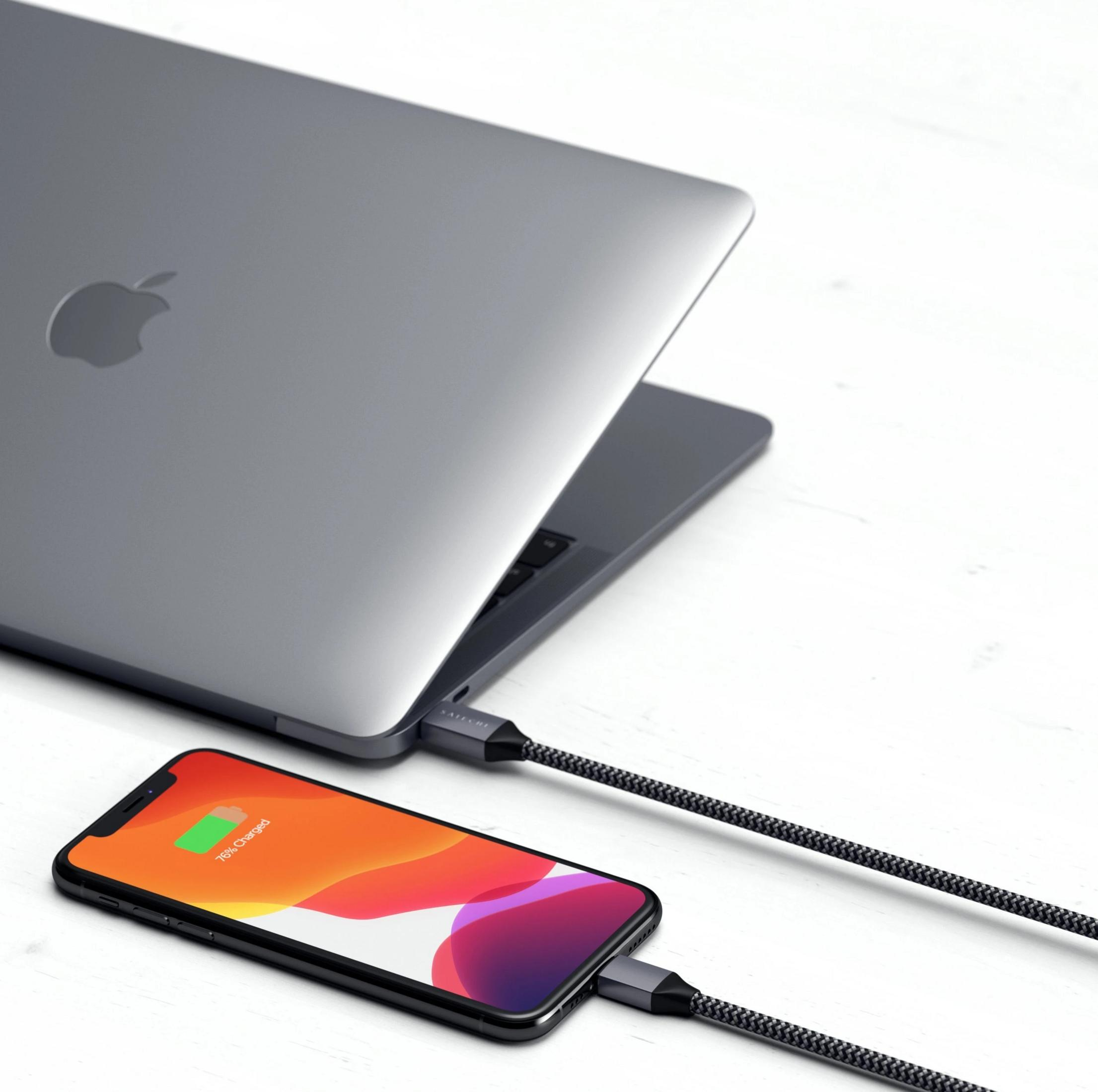 Ein MacBook wird über ein geflochtenes Kabel mit einem iPhone verbunden, das zu 76% aufgeladen ist.