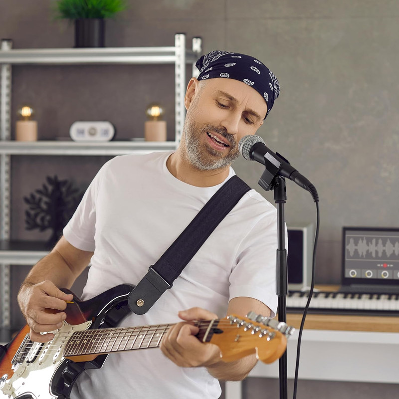 Mann mit Bandana singt ins Mikrofon und spielt Gitarre im Studio.