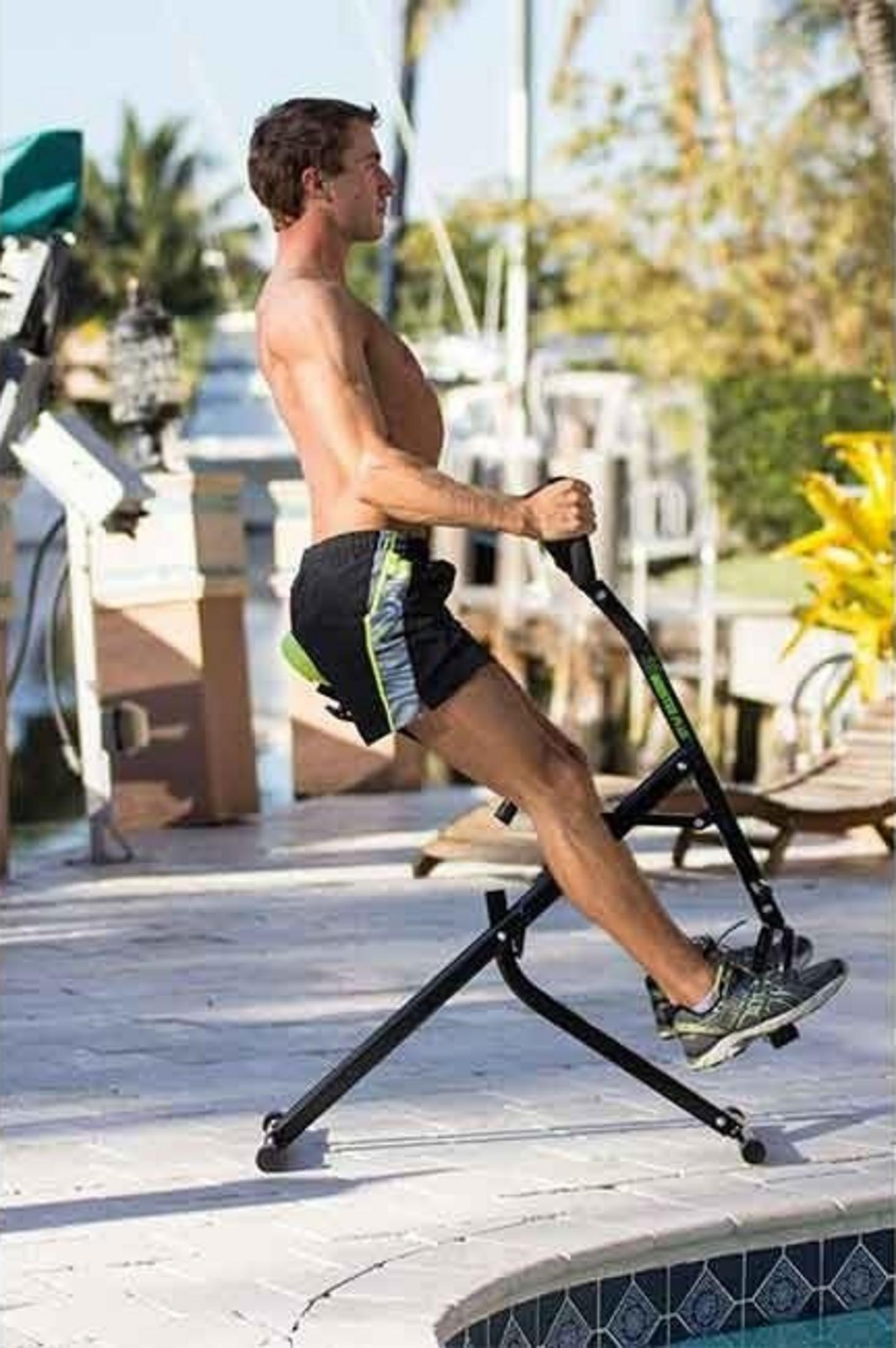 Mann trainiert auf einem Heimtrainer im Freien neben einem Pool.