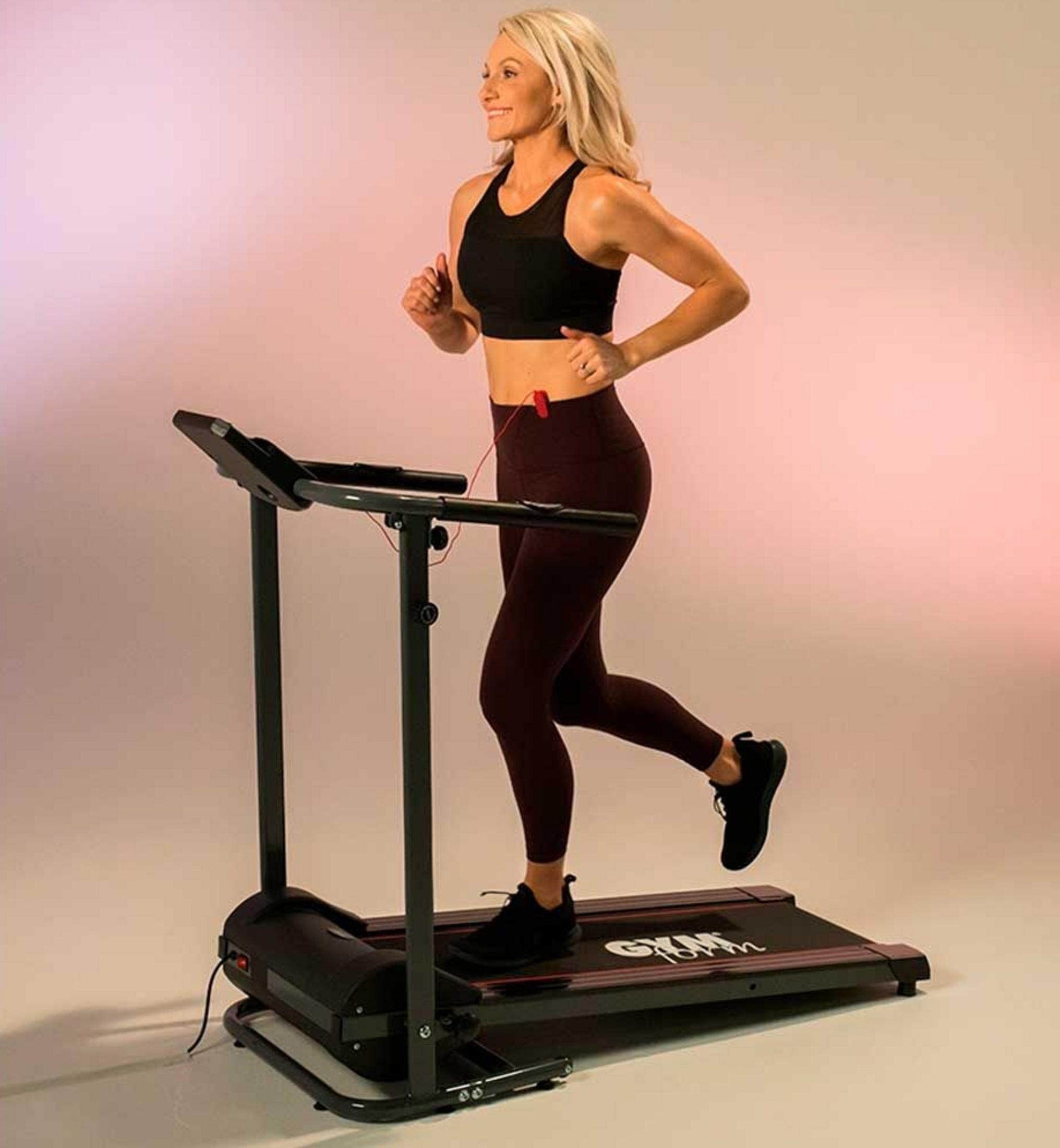 Eine Frau in Sportkleidung läuft auf einem Laufband in einem Studio.