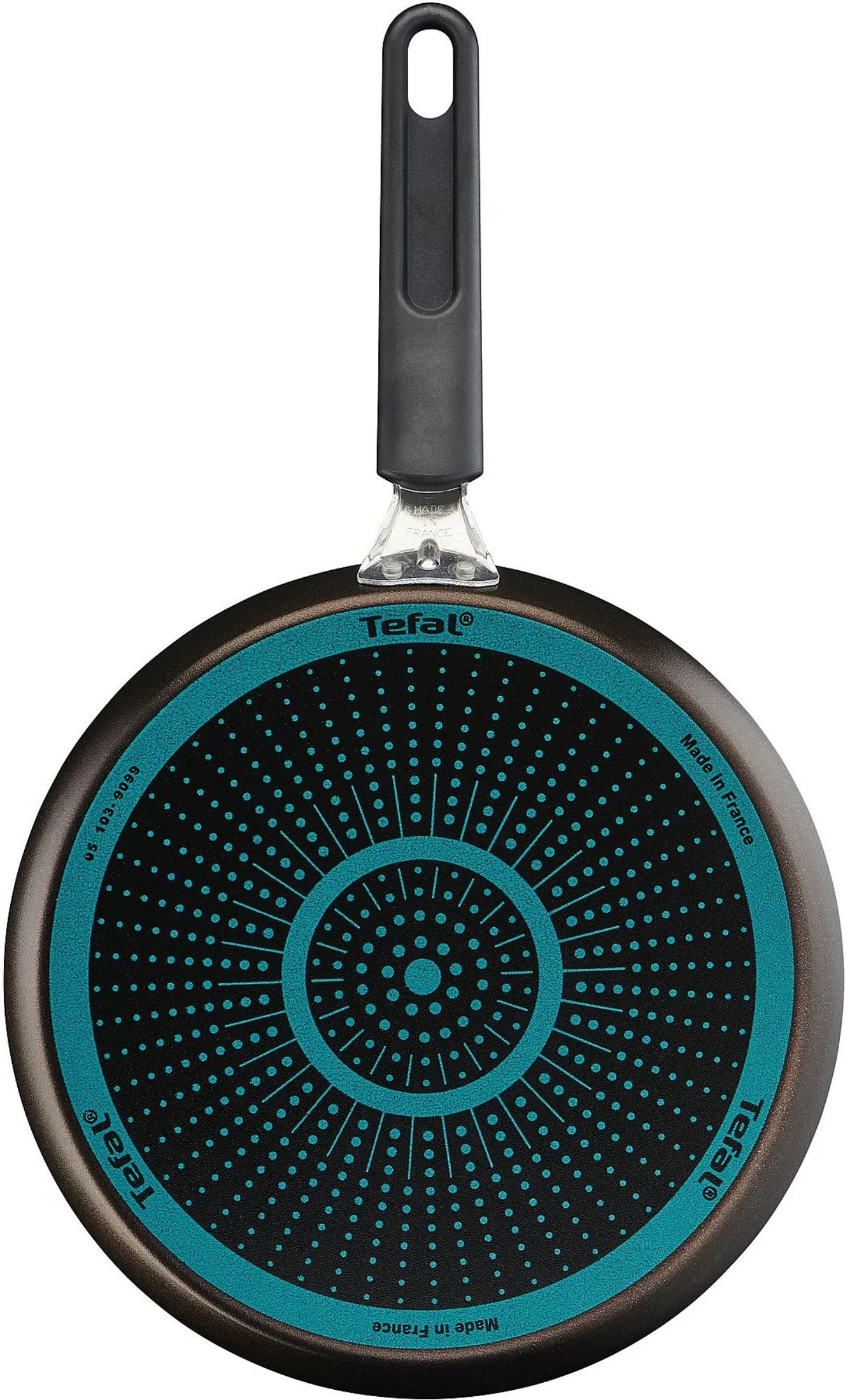 Czarna podstawa patelni Tefal z niebieskimi kropkami i koncentrycznymi okręgami. Czarna rączka.