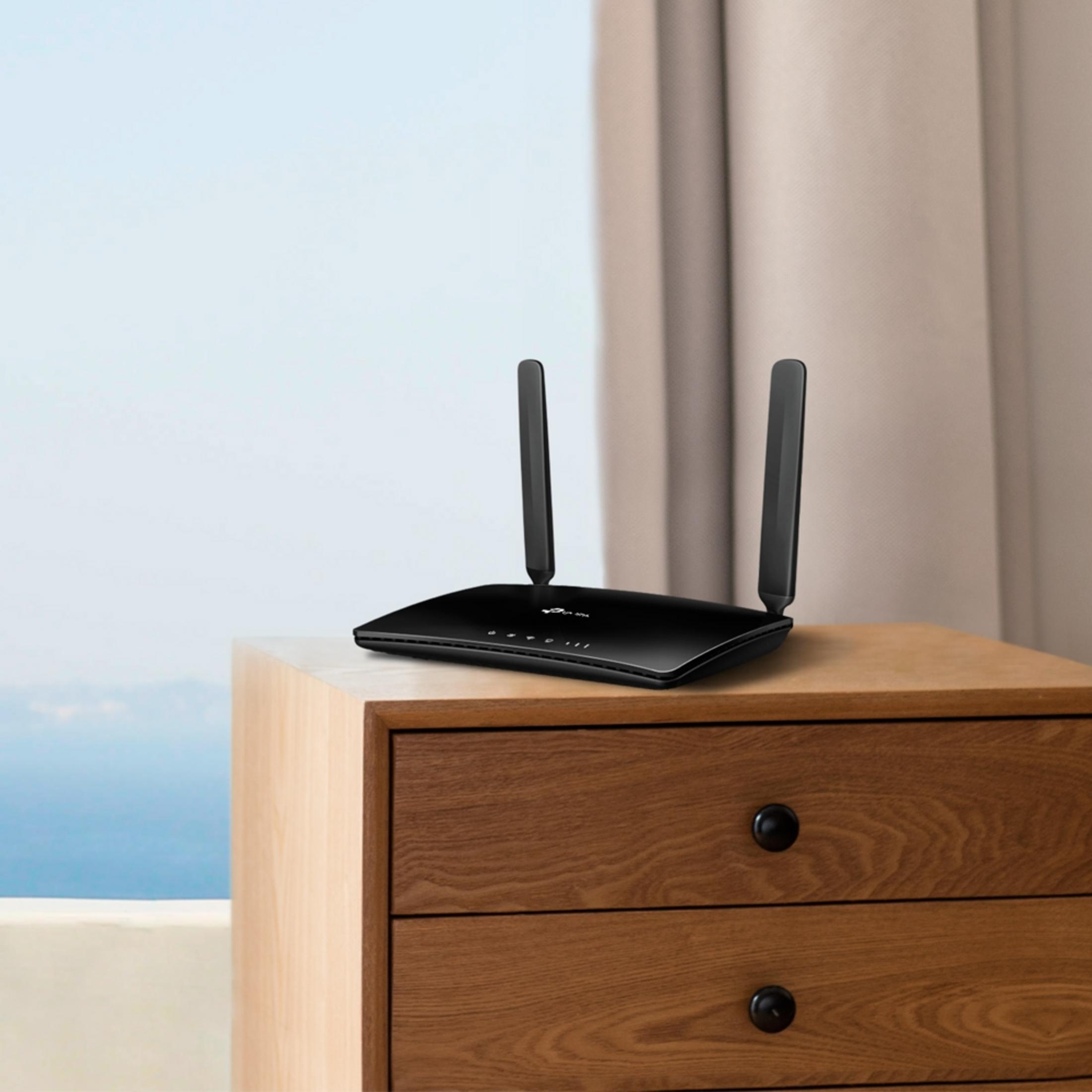 Schwarzer Router mit Antennen auf Nachttisch, Vorhang im Hintergrund.