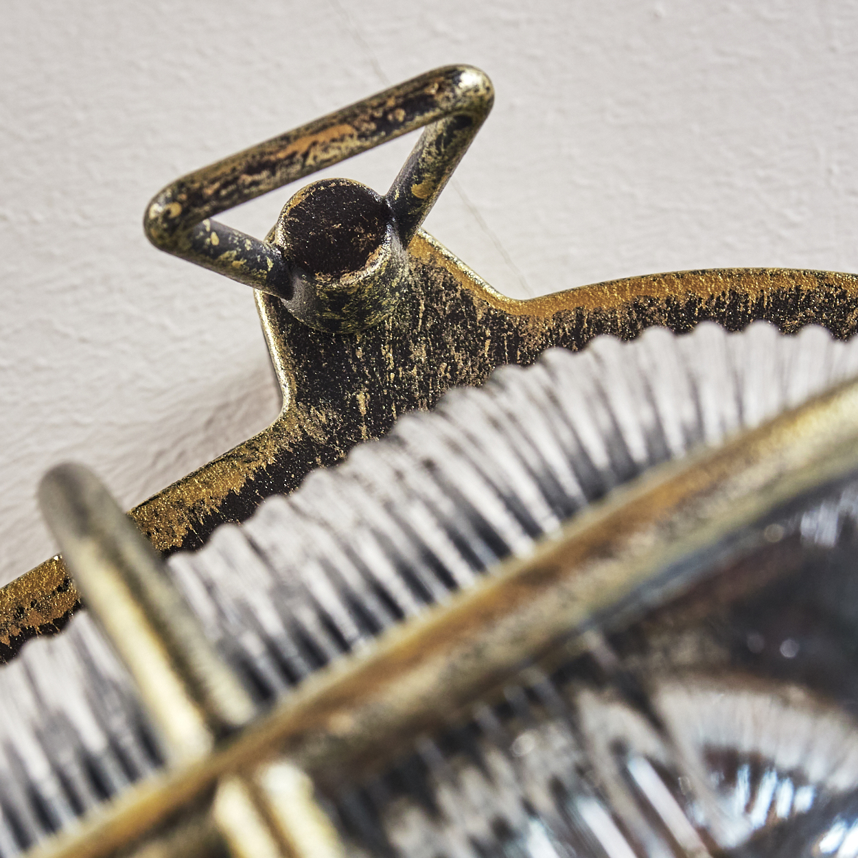 Nahaufnahme eines vergoldeten Metallanhängers mit zahnartiger Kante und Aufhänger.