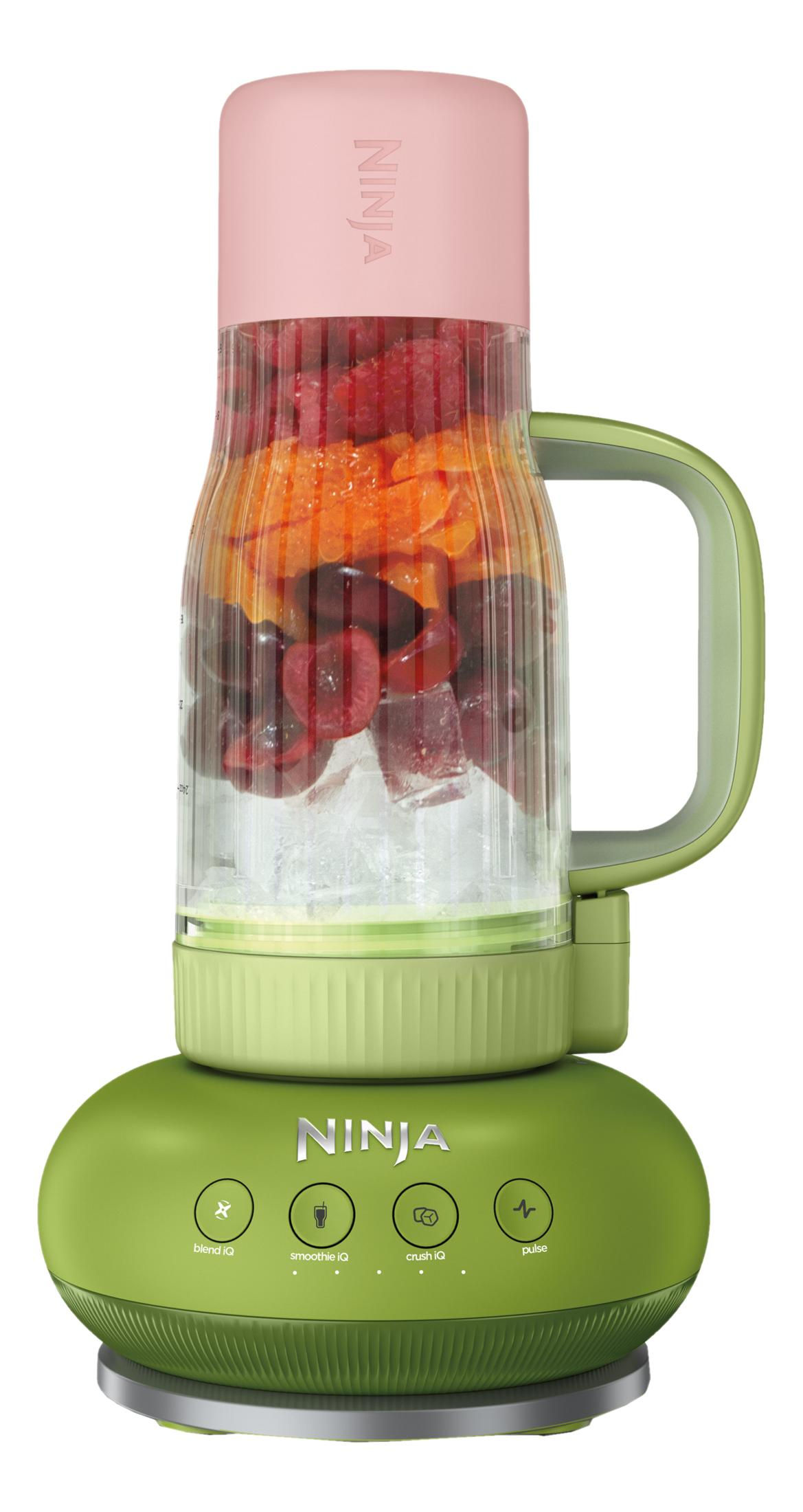 Grüner Ninja-Mixer mit rosa Deckel. Behälter enthält Eis, Kirschen und Orangenscheiben.
