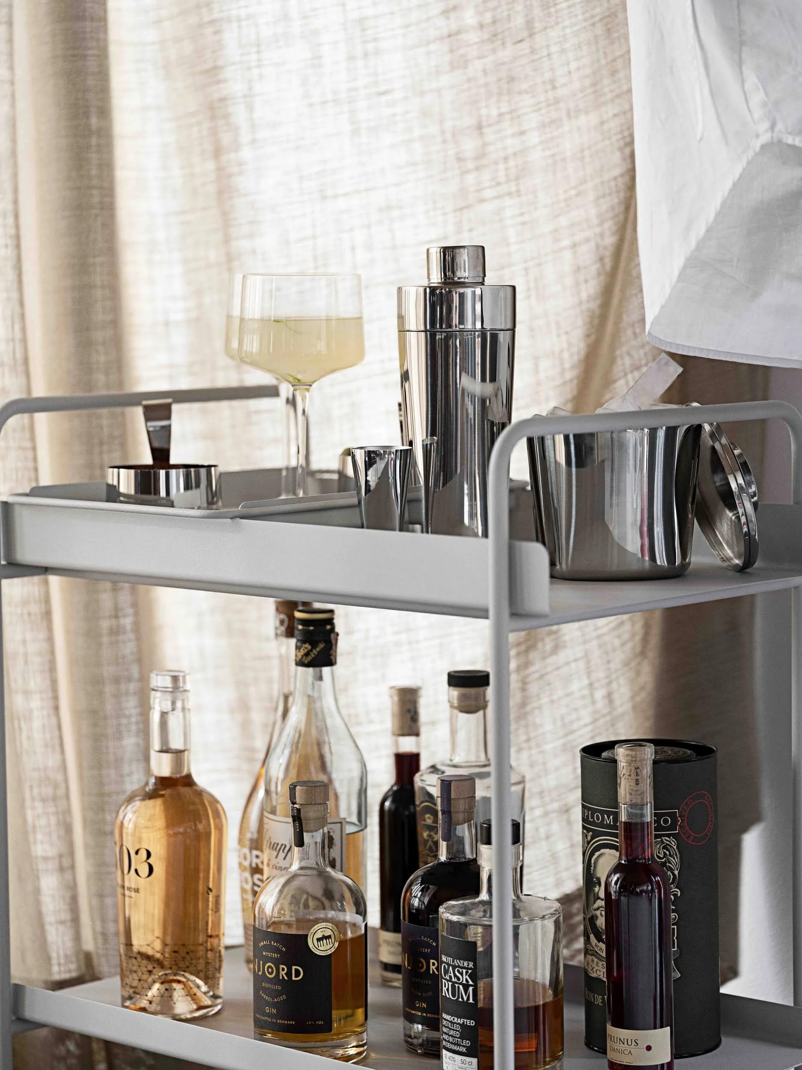 Un carrello da bar fornito di bottiglie e accessori per cocktail.