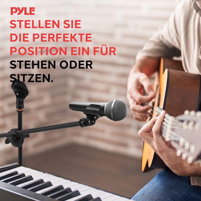 Ein Mann spielt Gitarre neben einem Mikrofonständer und einem Keyboard.