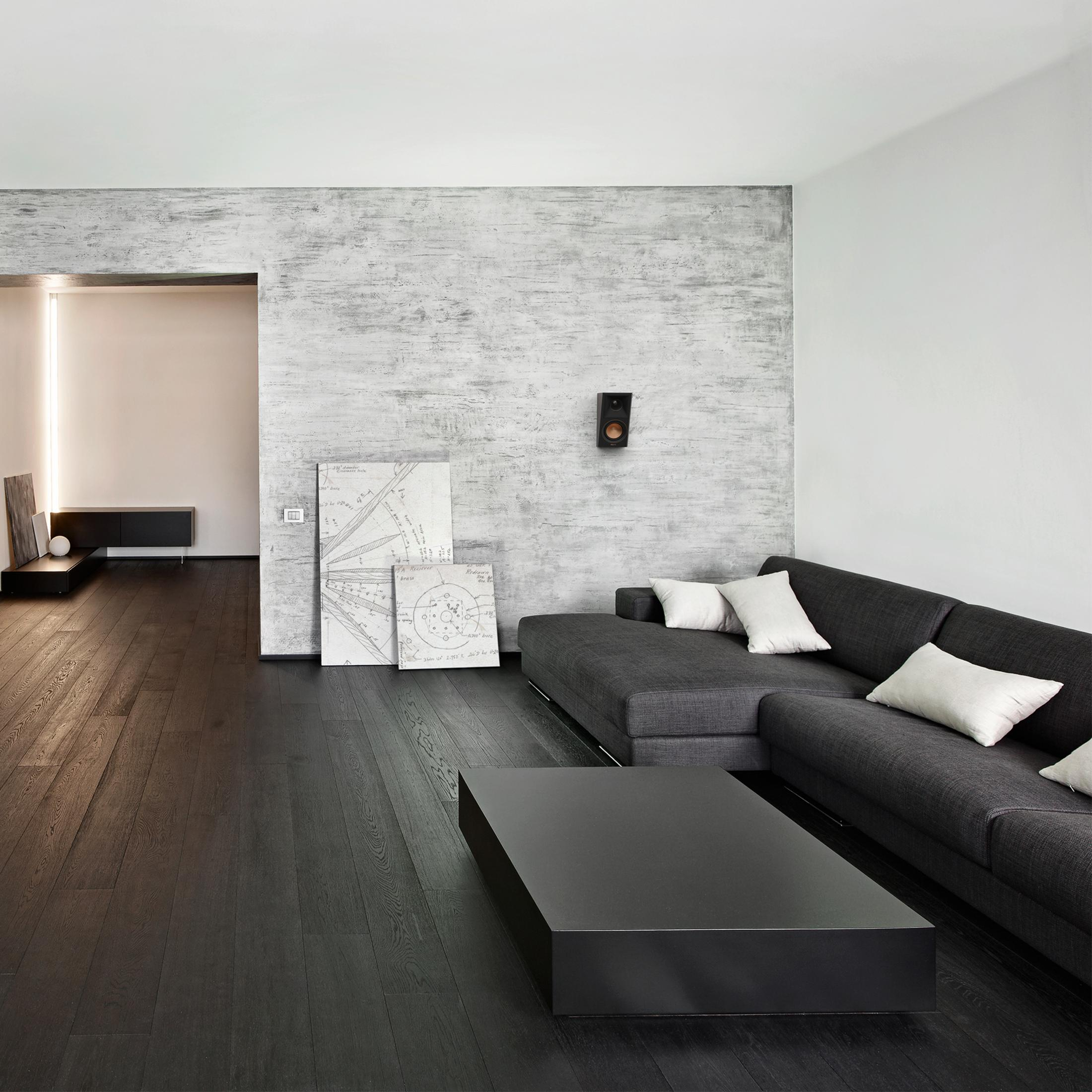 Un soggiorno scuro con divano angolare, tavolo nero e pavimenti in legno.