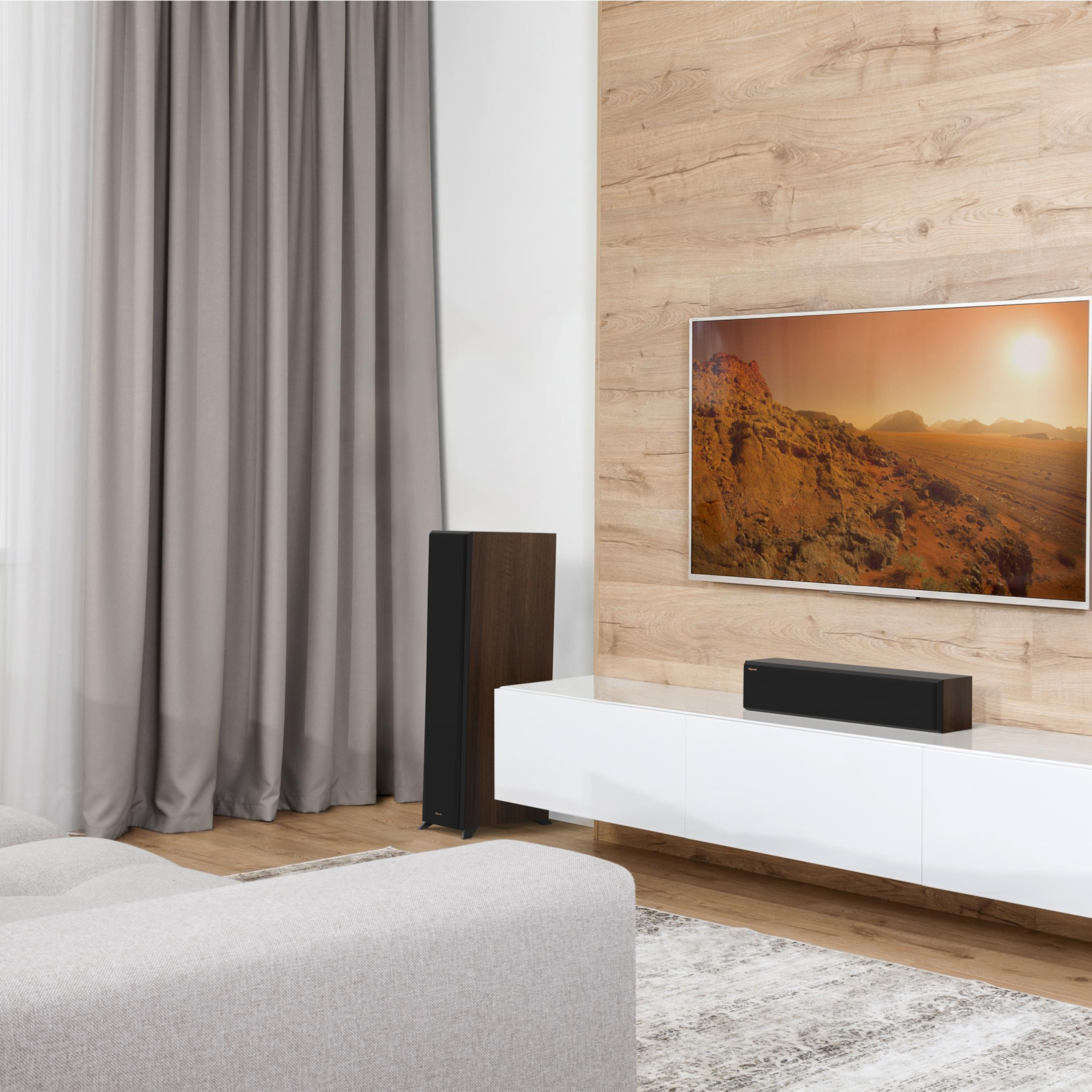 Ein Wohnzimmer mit Sofa, Fernseher, Lautsprecher und Vorhängen.