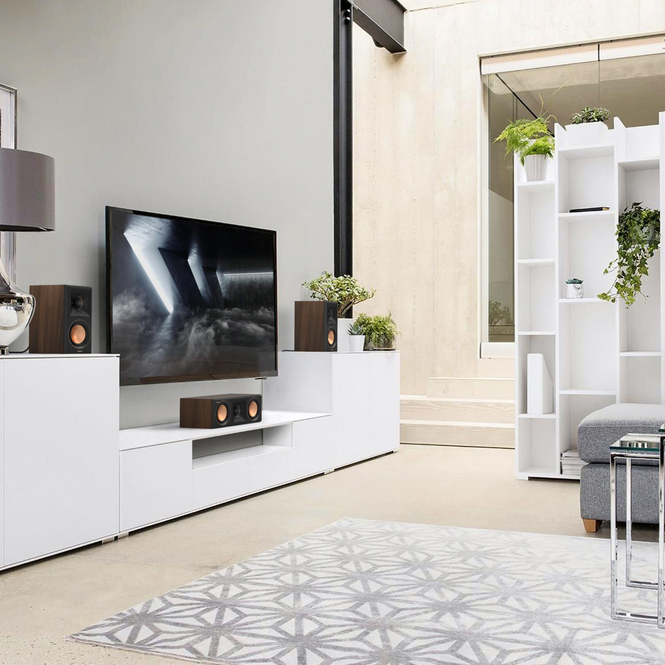 Modernes Wohnzimmer mit Fernseher, Lautsprechern, Bücherregal und Teppich.