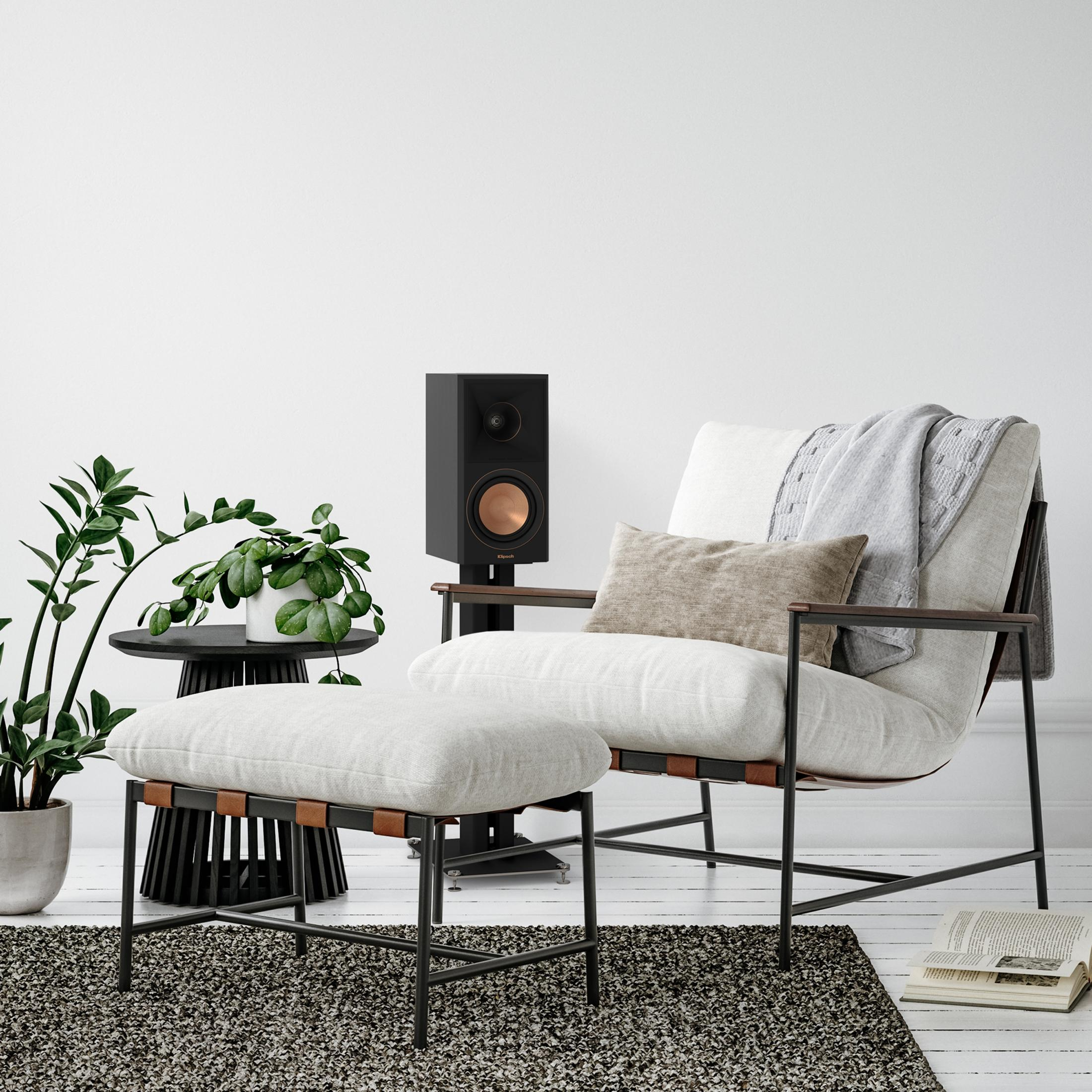 Una poltrona con tavolino, altoparlante e piante in una stanza moderna.