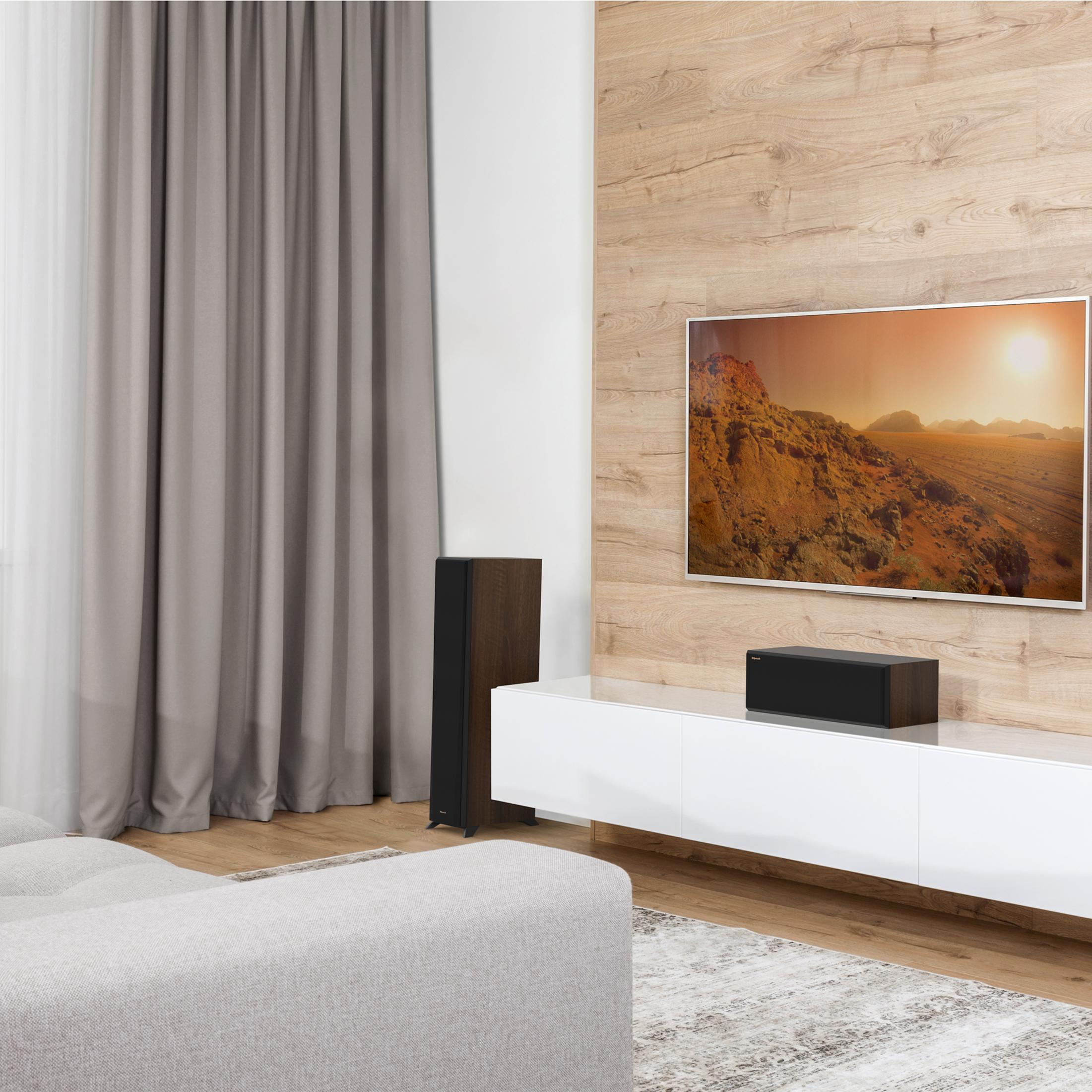 Ein Wohnzimmer mit Fernseher, Lautsprechern, Sofa und Vorhängen.