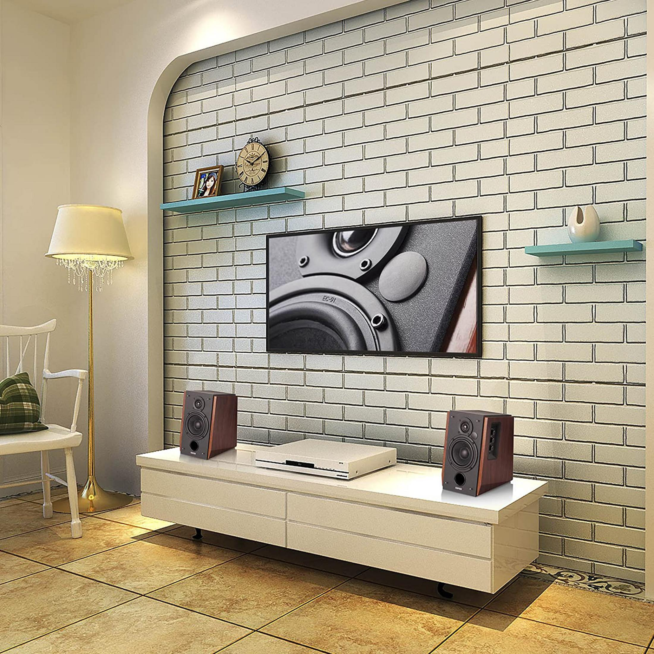 Ein Wohnzimmer mit einem weißen TV-Schrank, Lautsprechern, einem Fernseher und einer Lampe.