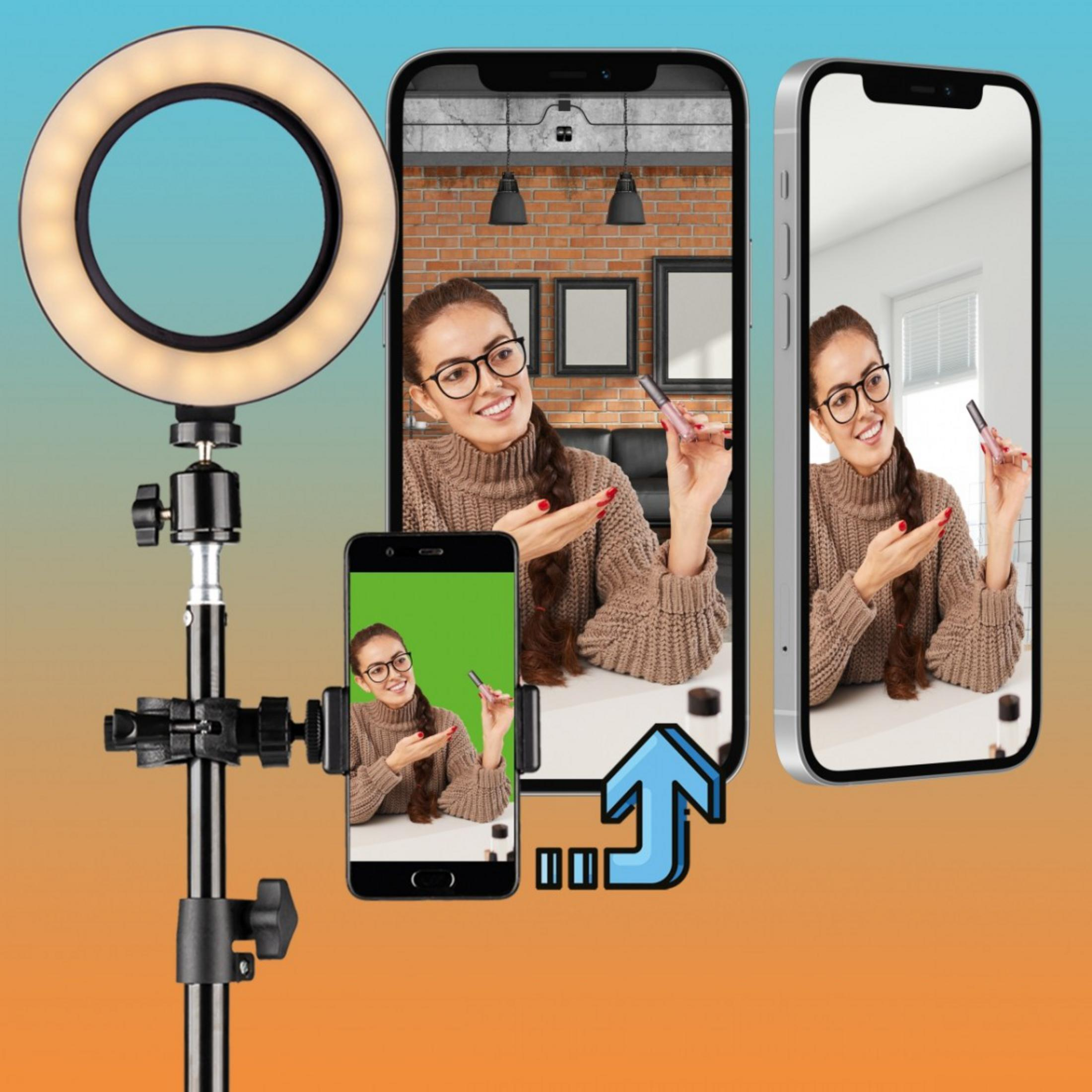Una donna con occhiali tiene rossetto davanti a un ring light e smartphone.