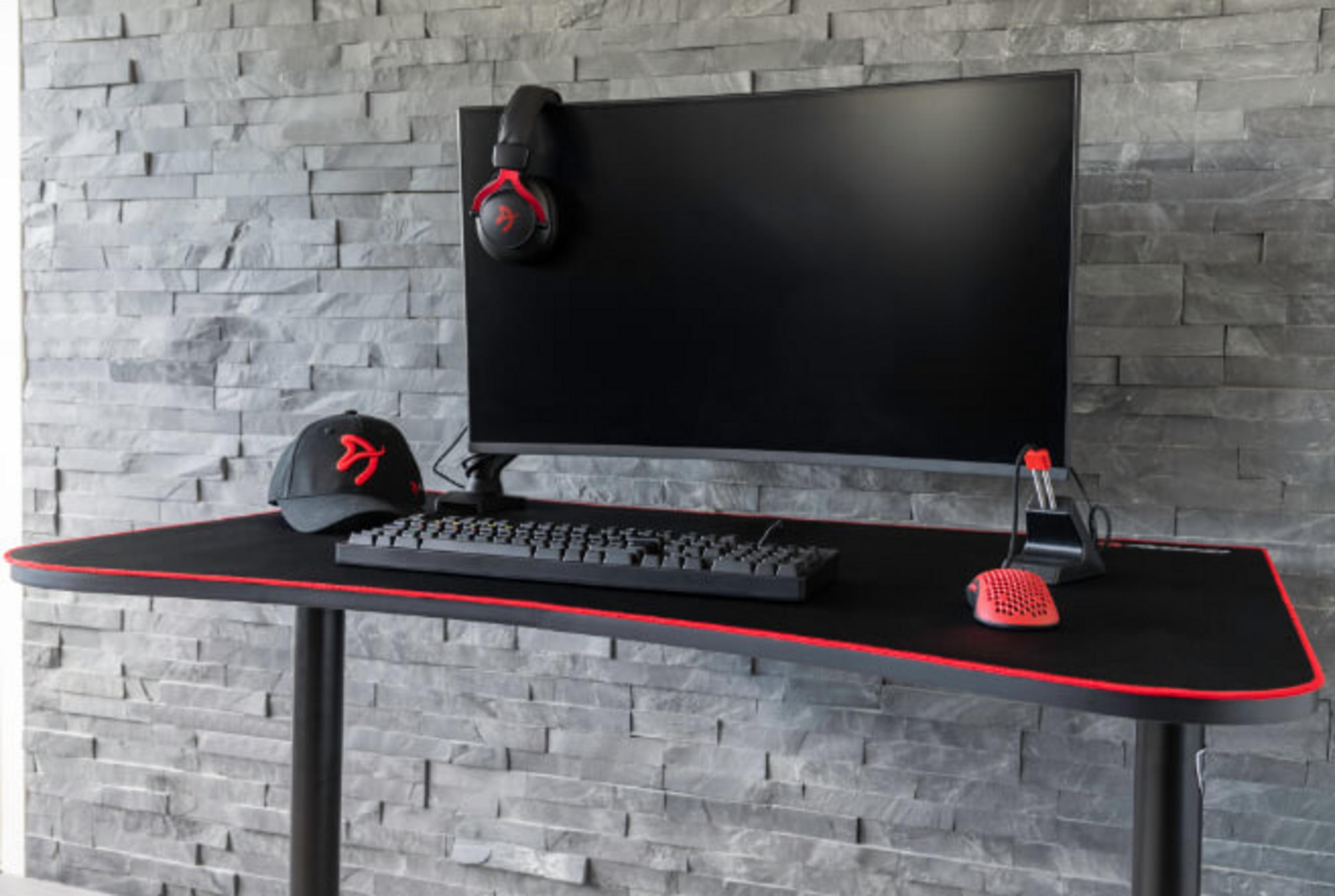 Una scrivania da gaming con monitor, tastiera, mouse e cuffie neri.