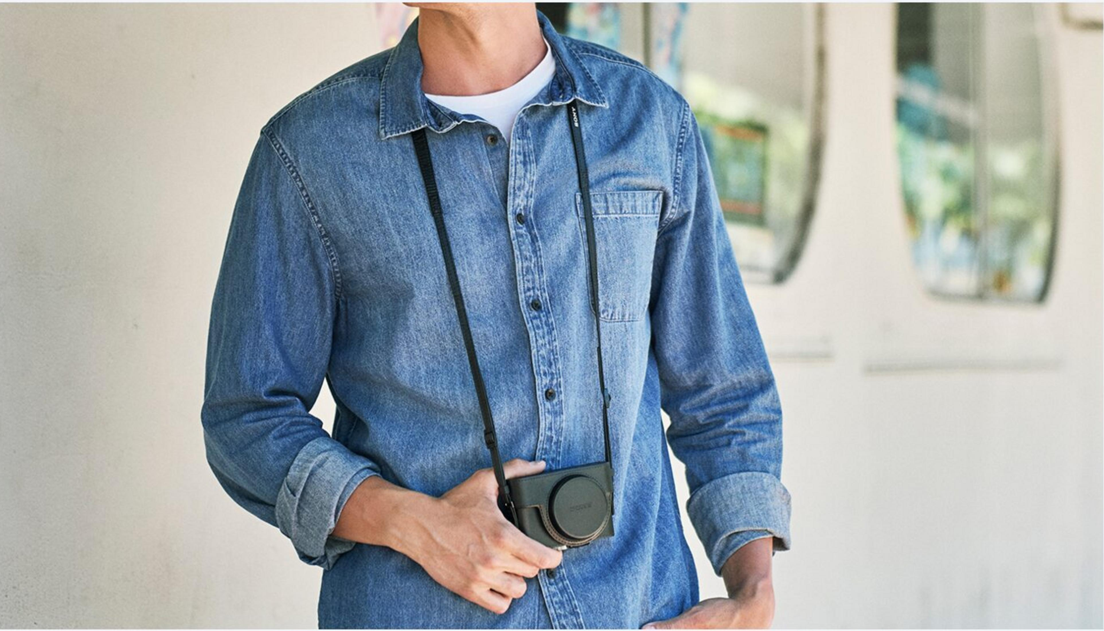 Hombre con camisa de mezclilla y cámara al cuello.