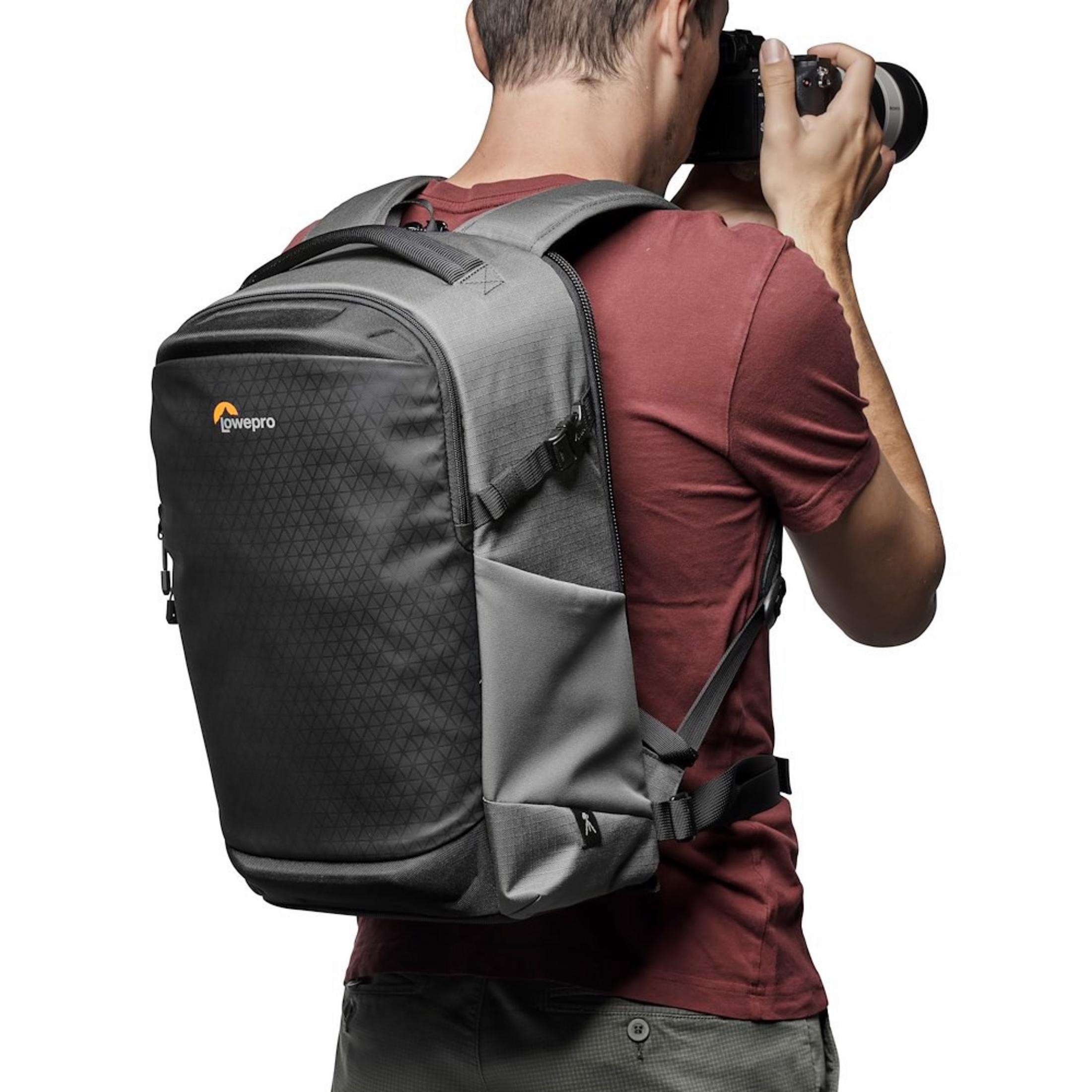 Man with backpack takes a photo with a camera, white background.