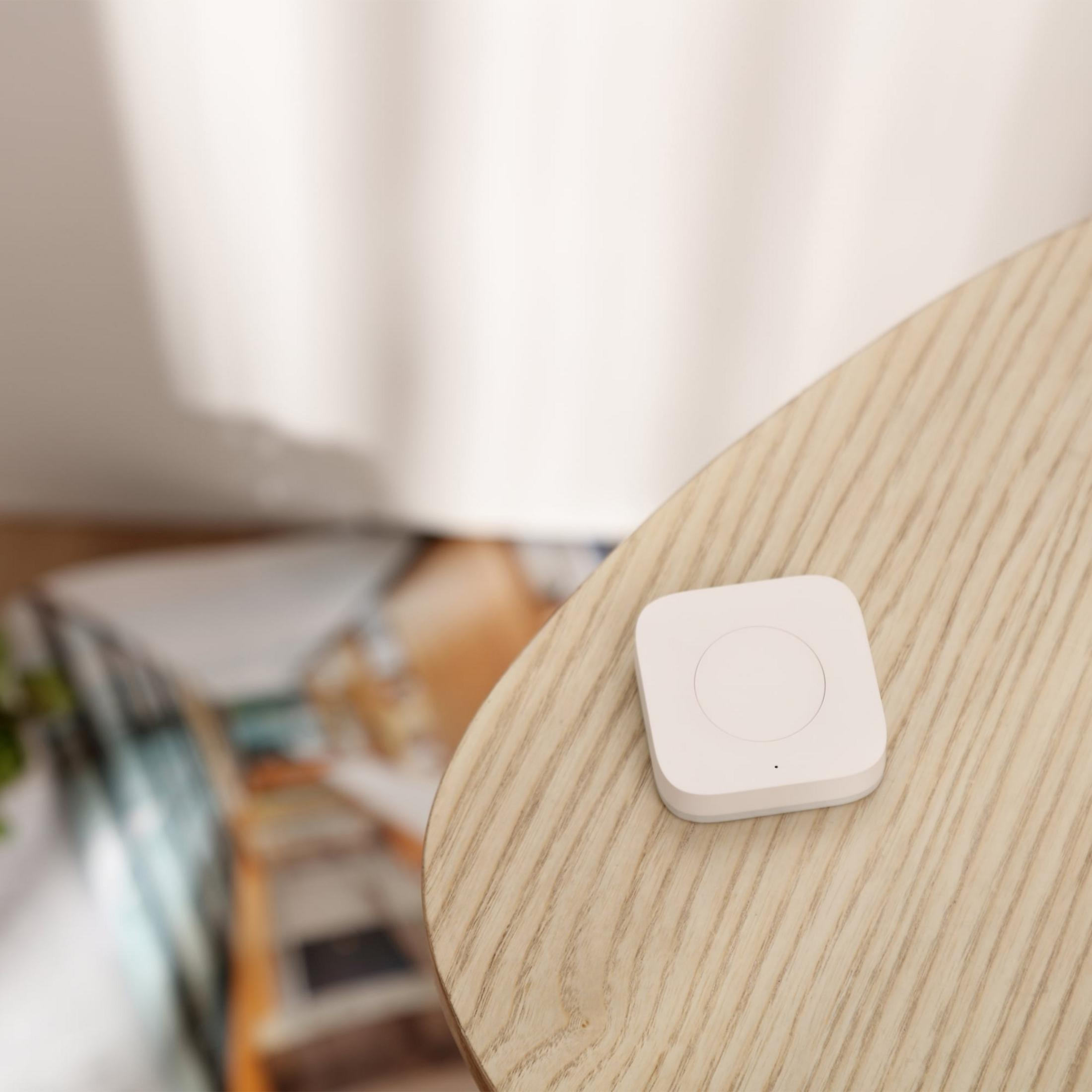 Un piccolo dispositivo bianco su un tavolo di legno, sfondo sfocato.