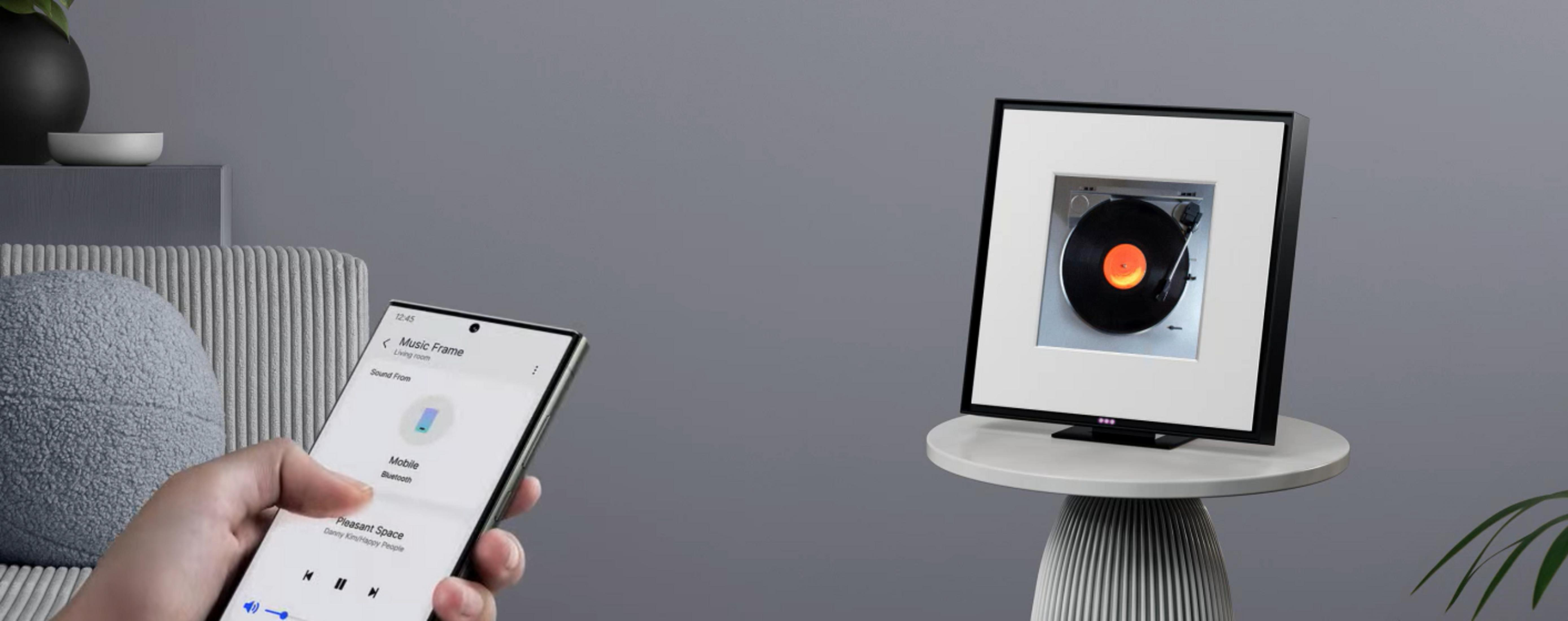 Uno smartphone controlla una cornice musicale che mostra un disco in vinile su un tavolo.