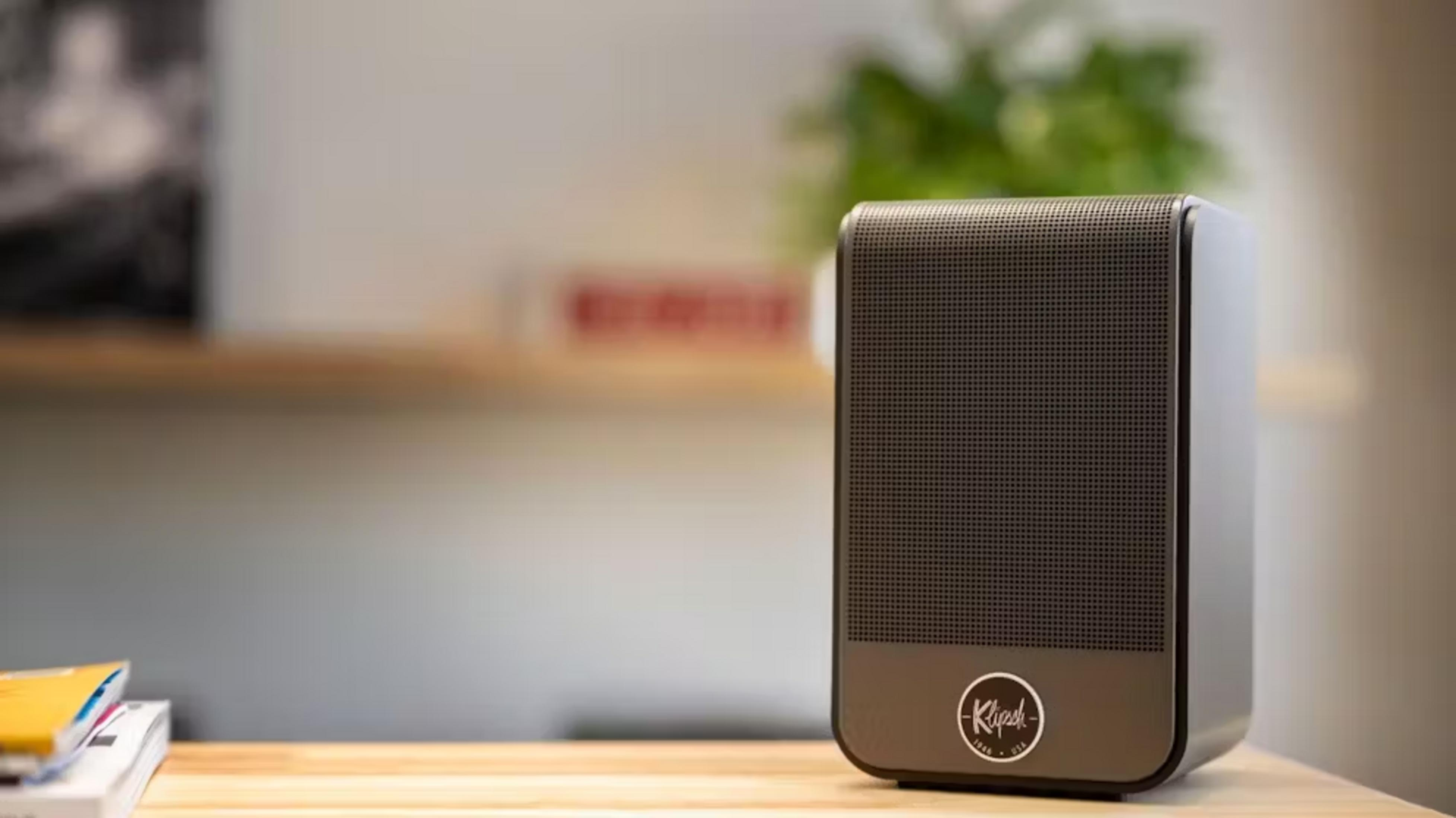 Ein dunkler Lautsprecher mit dem Klipsch-Logo steht auf einem Holztisch.