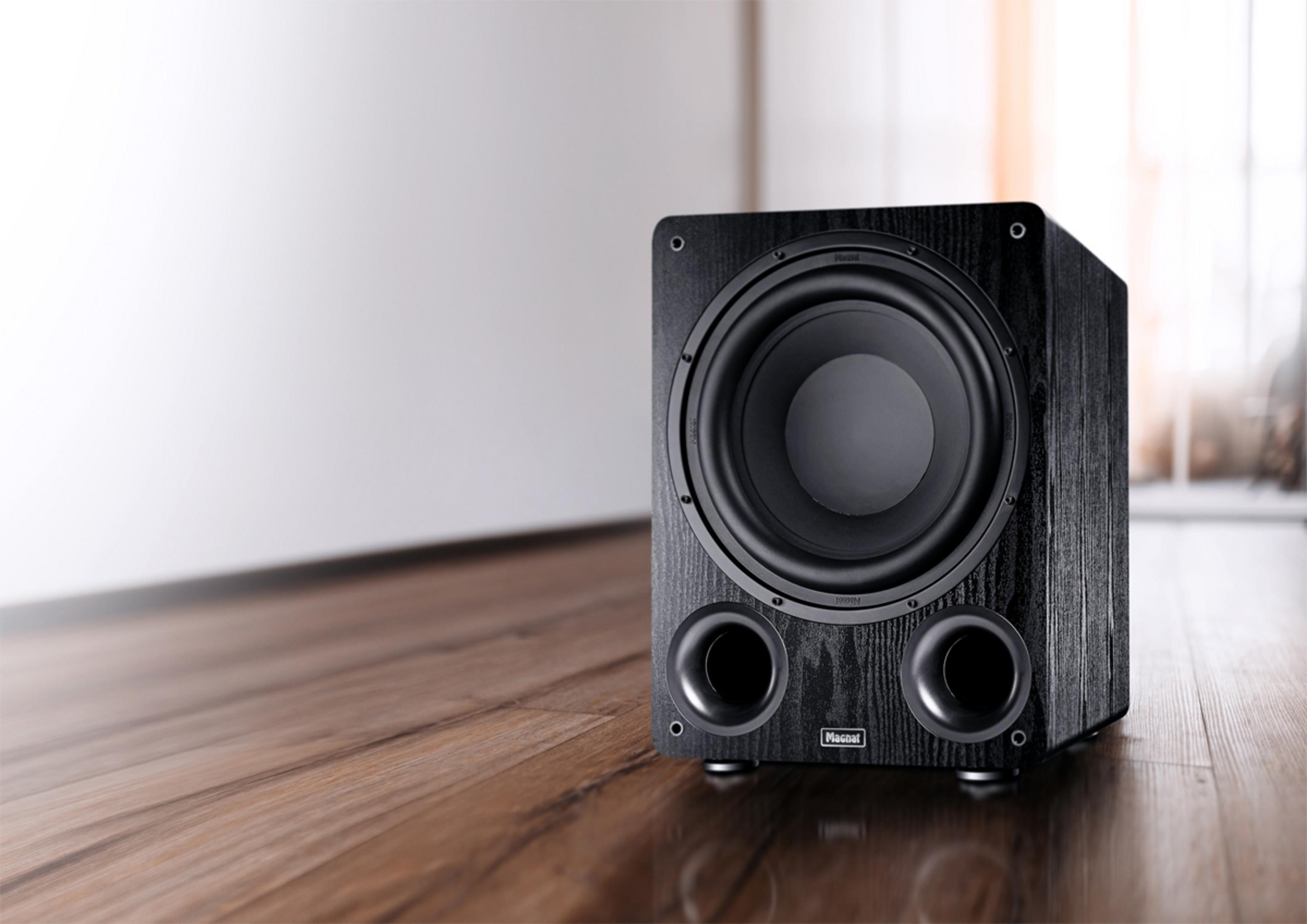 Schwarzer Subwoofer mit Bassreflexrohren auf Holzboden.