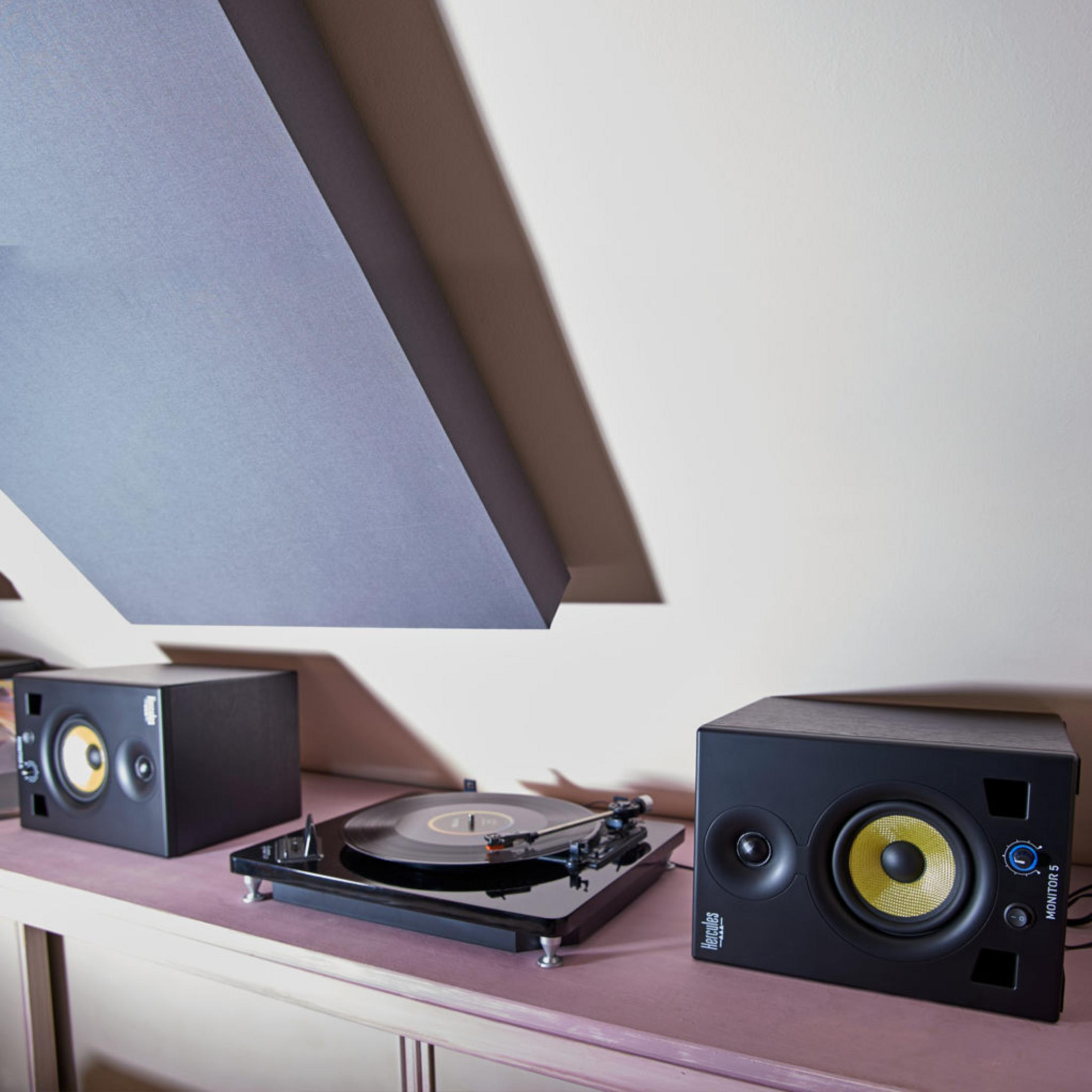 A turntable with a vinyl record and two black speakers on a shelf.