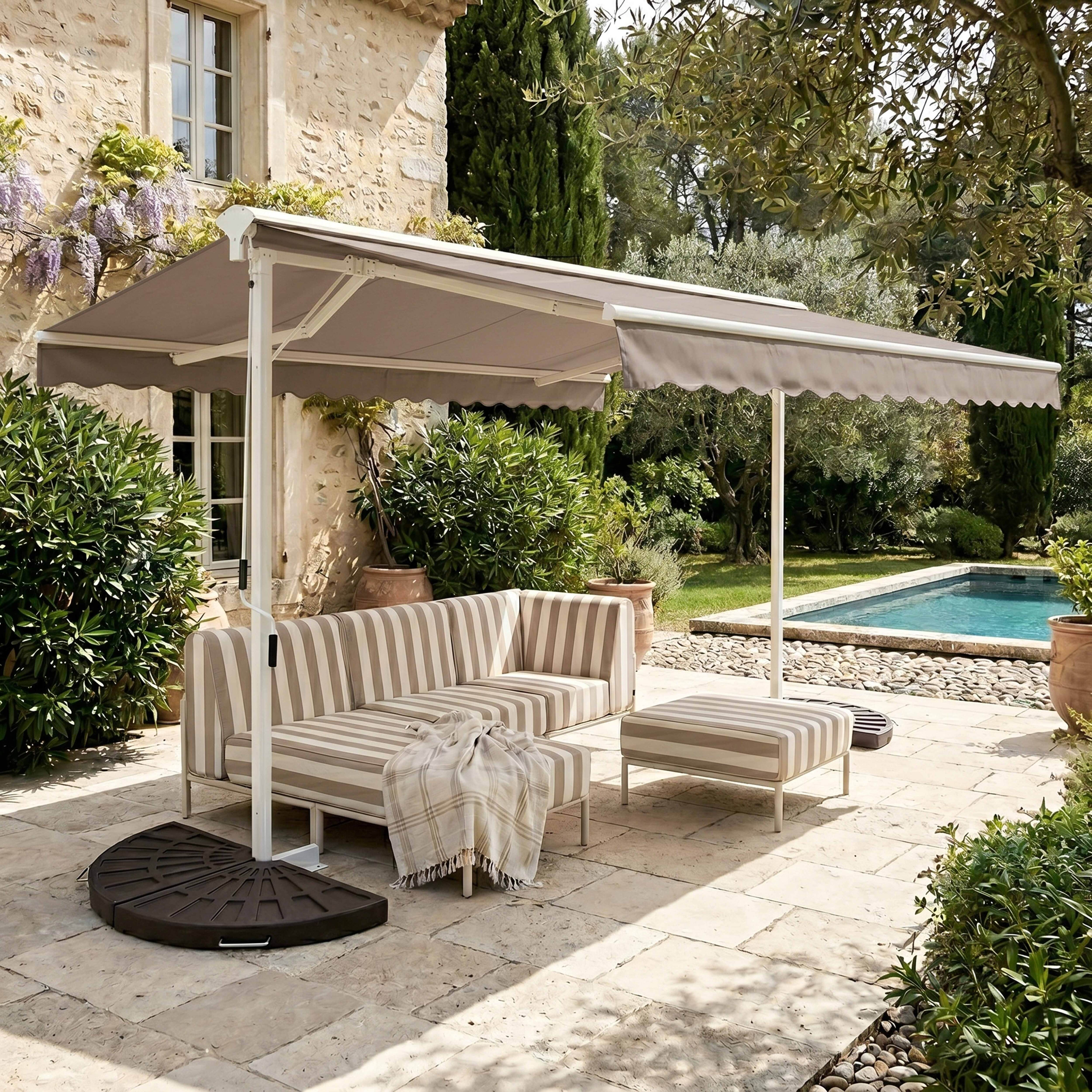 Ein gestreiftes Sofa und Hocker unter einem Sonnenschirm neben einem Pool.