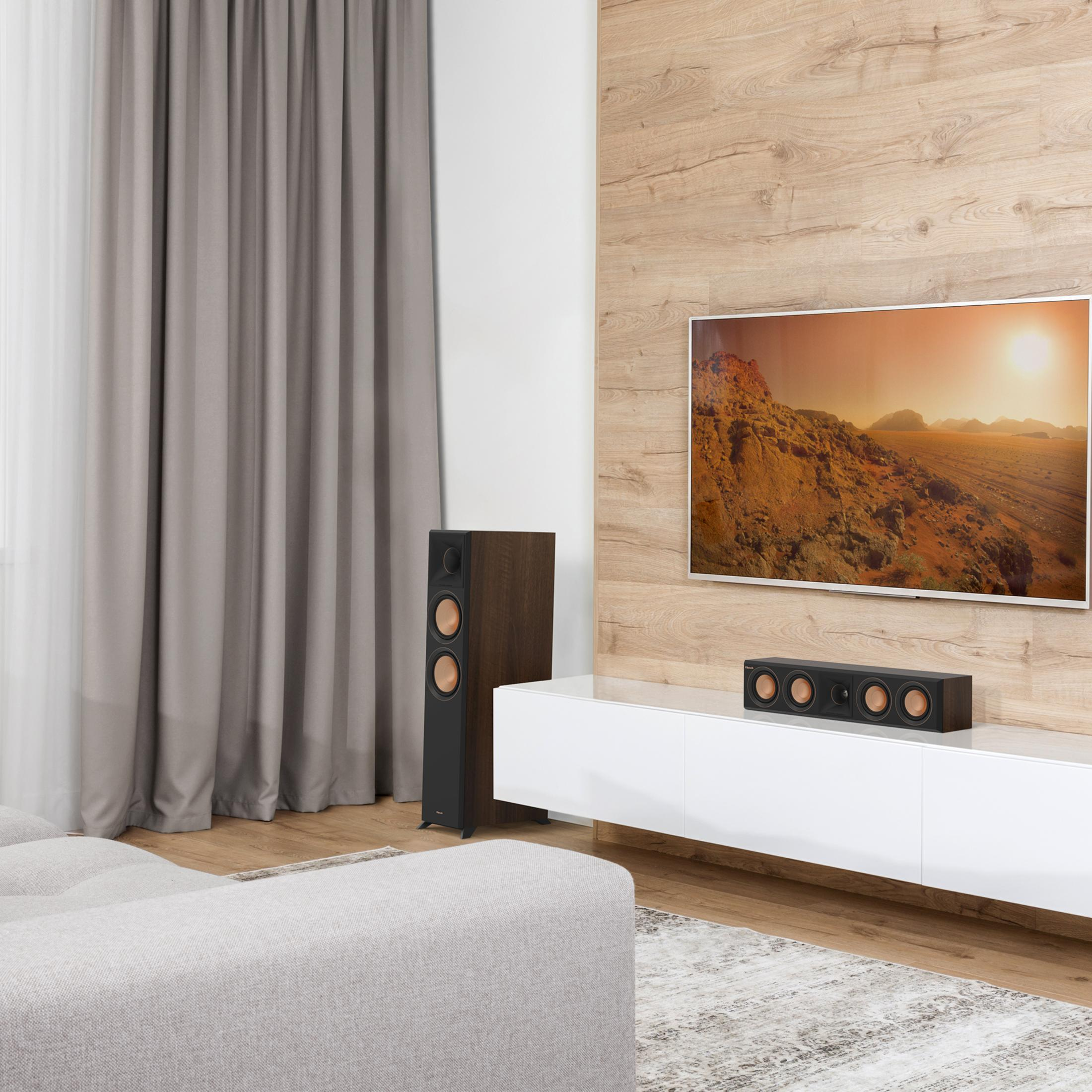Ein Wohnzimmer mit Fernseher, Lautsprechern und Sofa.