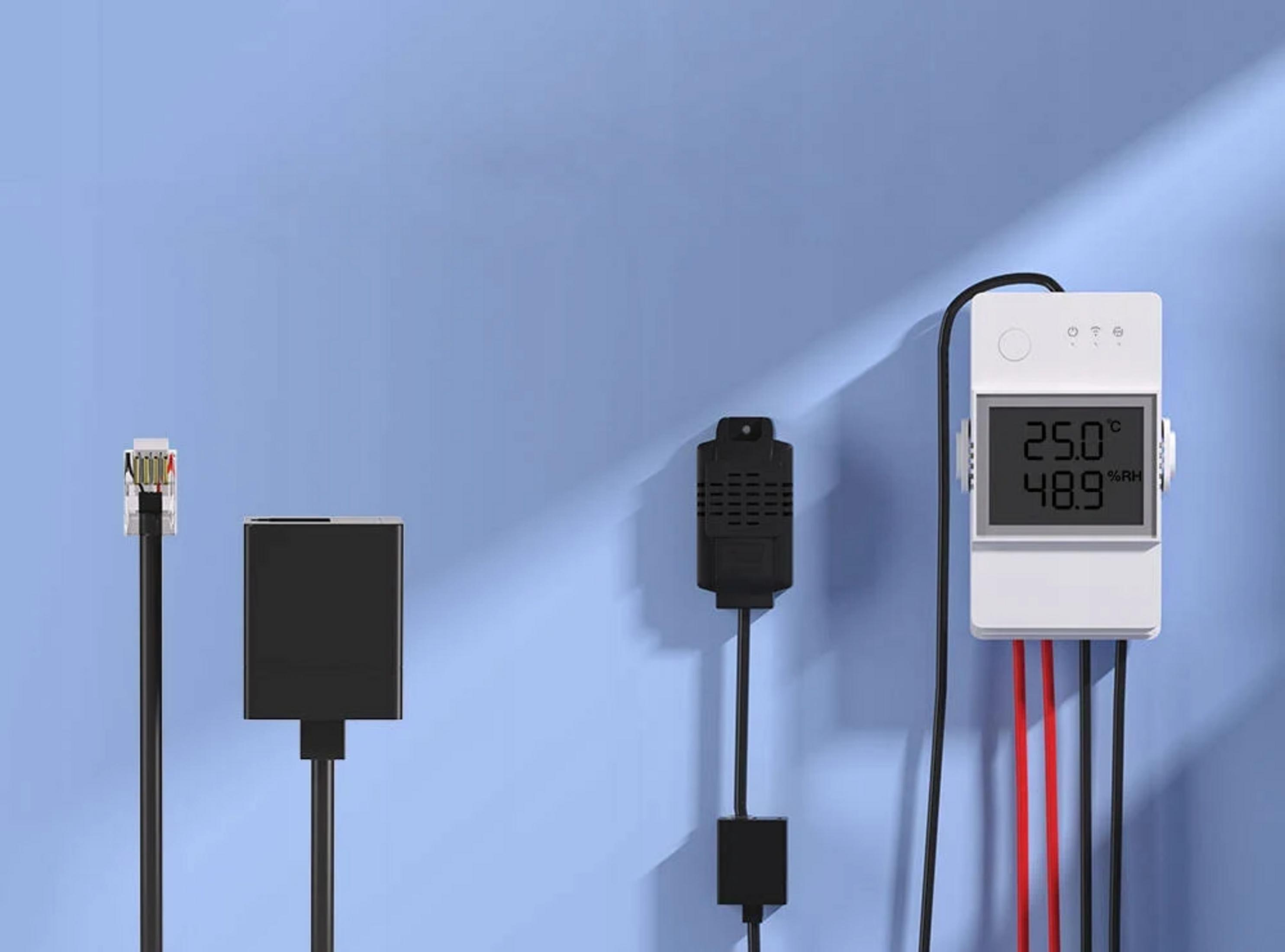 Un dispositivo bianco mostra 25.0°C e 48.9% RH, con cavi neri e rossi nelle vicinanze.