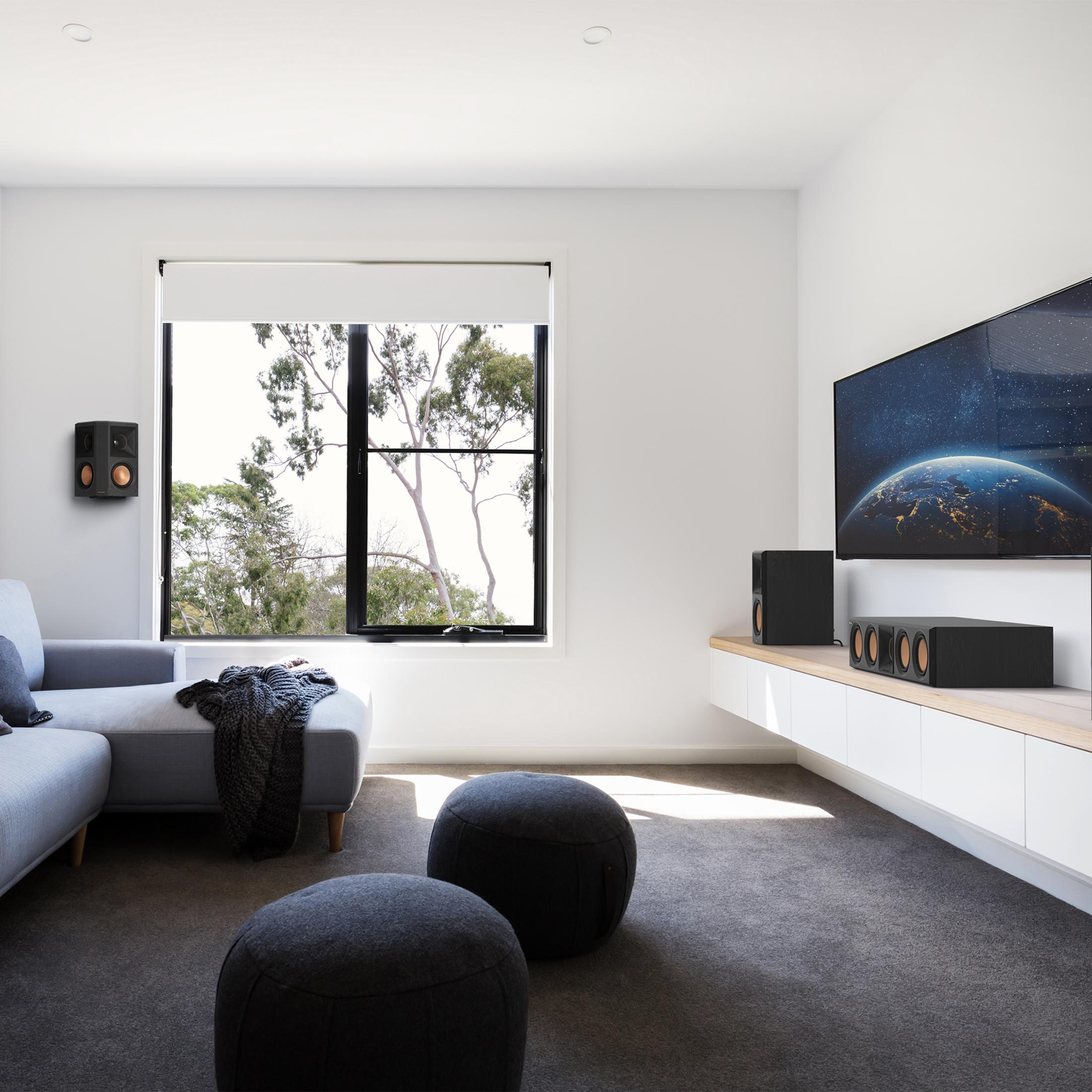 Un soggiorno moderno con divano angolare grigio, pouf e grande TV che mostra la Terra.