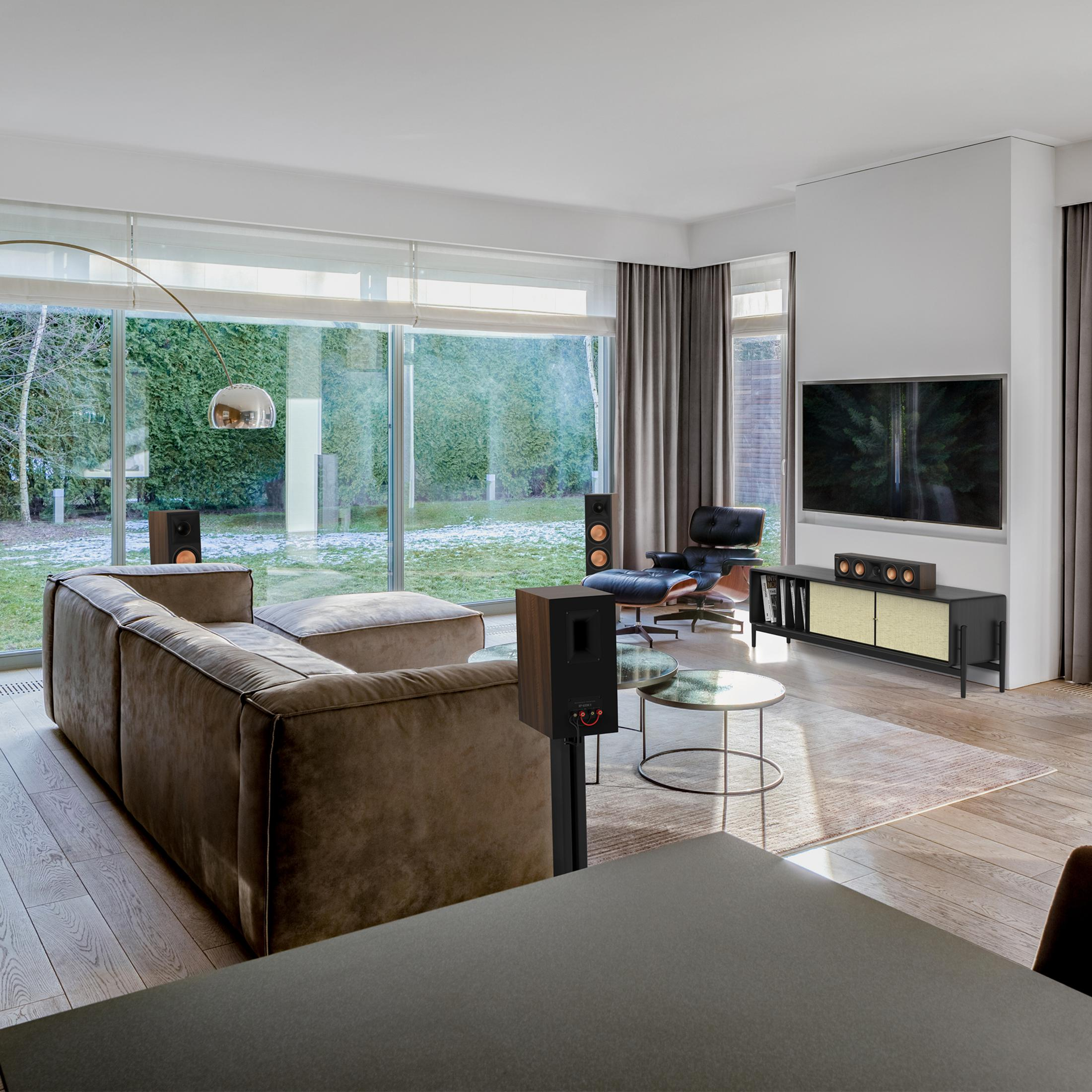 Ein modernes Wohnzimmer mit brauner Eckcouch, schwarzem Ledersessel und großen Fenstern.