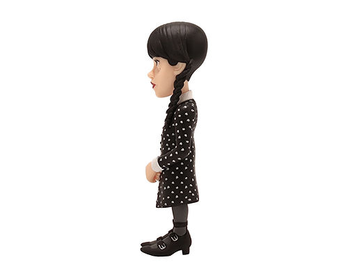 Eine Figur von Wednesday Addams mit Zöpfen und schwarzem Kleid mit weißen Punkten.
